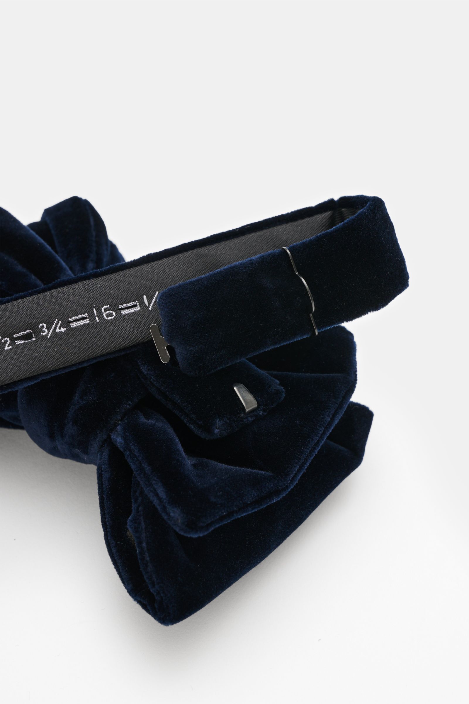 Close-up side view of a Tom Ford Samt-Schleife dunkelblau, a dark blue velvet bow tie made of viscose and cupro, featuring a soft touch, material-typical appearance, tied design, and made in Italy.  

Samt aus Viskose und Cupro
weicher Gr