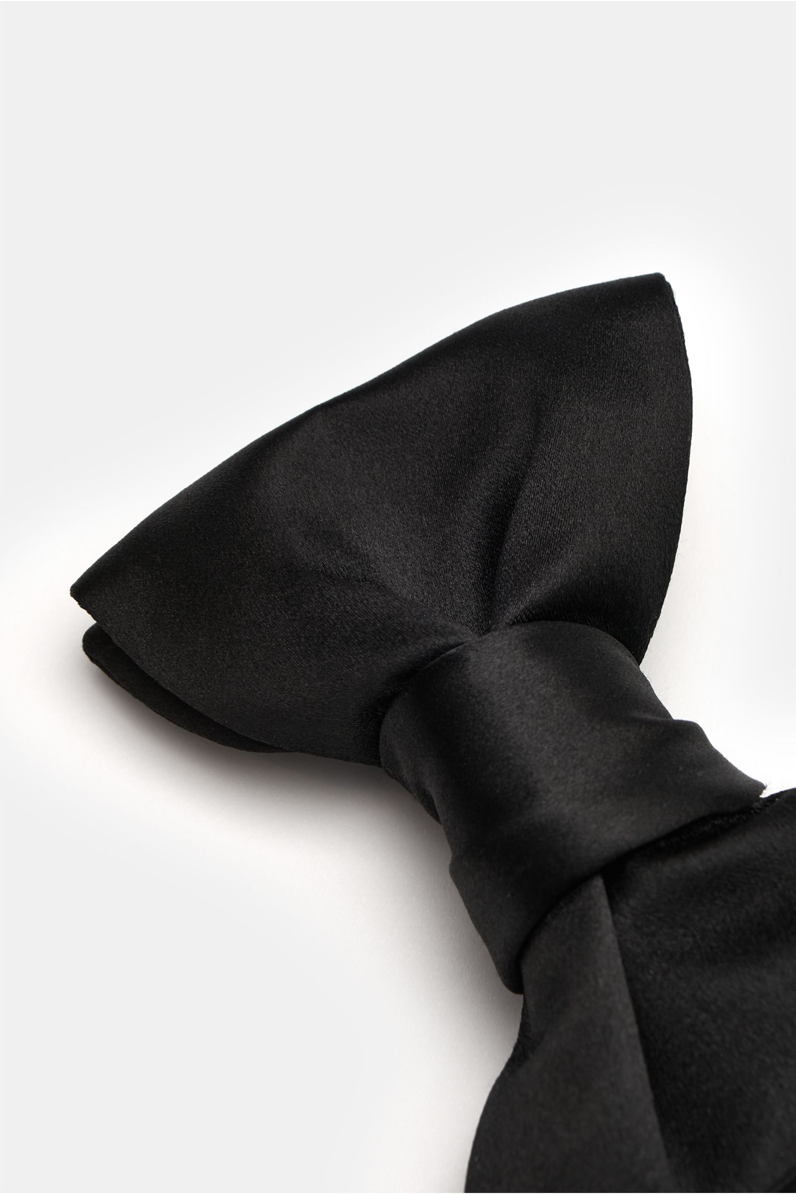 Close-up top-side view of the Tom Ford Seidenschleife schwarz, an elegant black silk satin bow tie with a slight sheen, width approx. 10.5 cm.

Diese elegante gebundene Schleife von TOM FORD besteht aus luxuriösem Seidensatin und ist das perfekte Finis