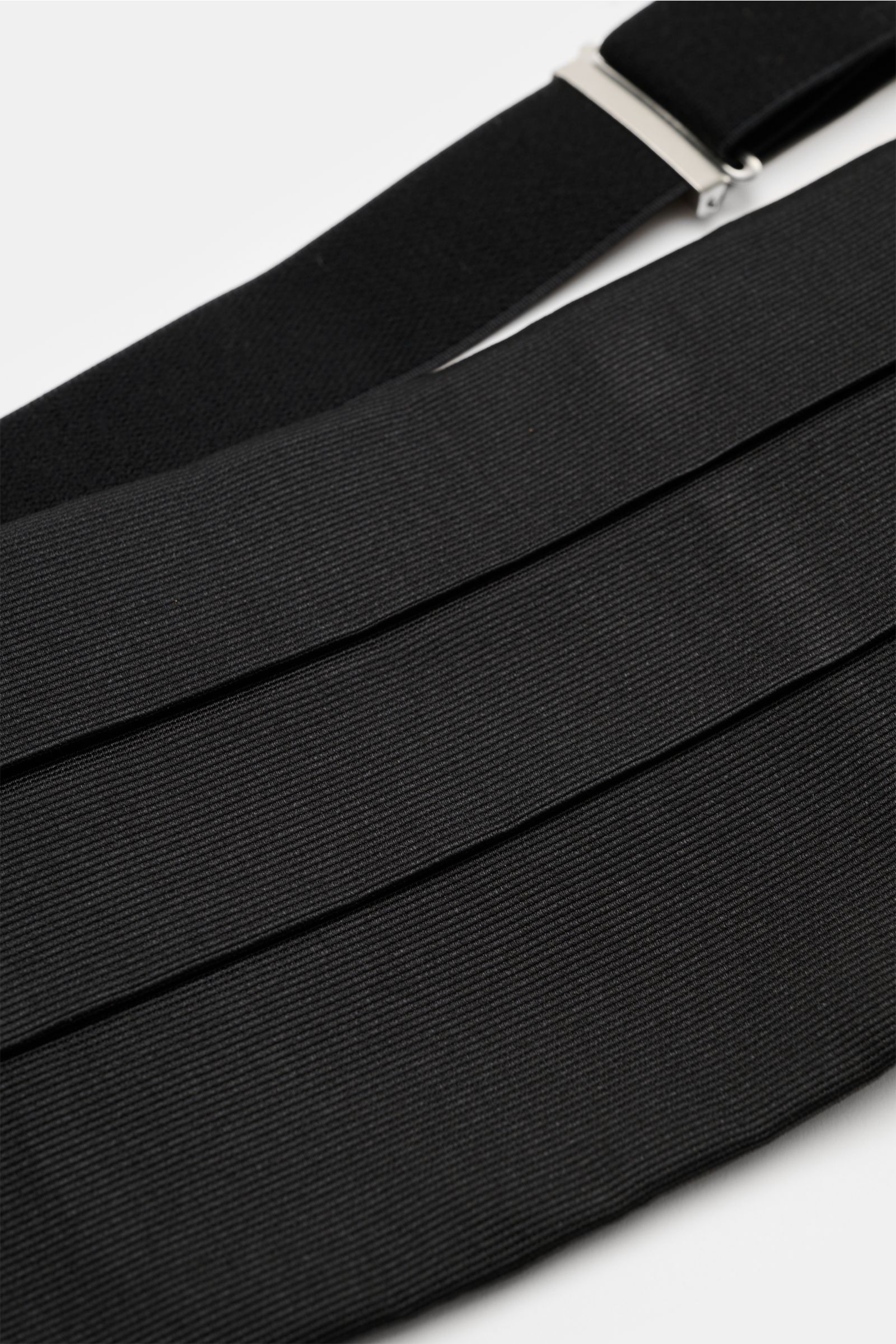 Close-up of Laco Abendaccessoire, a black textured fabric with pleats and a metal clasp, photographed from an angled top view.