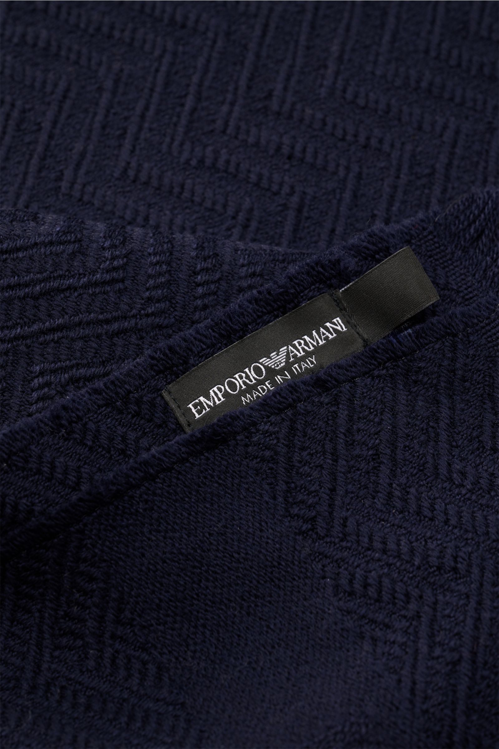 Close-up top view of the Emporio Armani Schal navy showing its tonal herringbone wool texture and logo label.

Italienische Eleganz für jeden Tag: Der edle Schal von EMPORIO ARMANI aus reiner Wolle überzeugt mit weichem Griff und markanter Webstruktur.