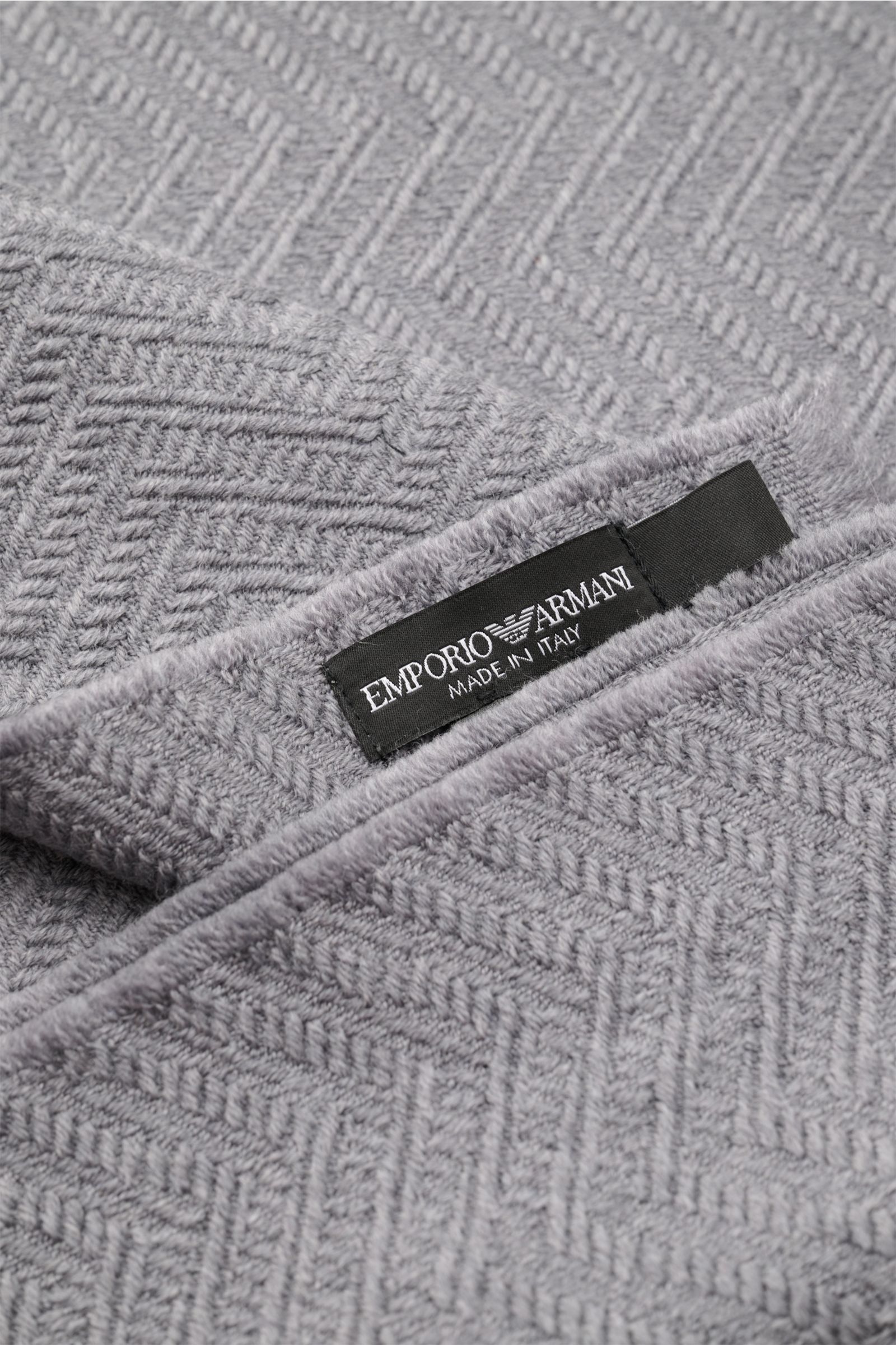 Emporio Armani Schal grau in Nahaufnahme, tonales Fischgrat-Webmuster, weiche reine Wolle mit Logo-Streifen und schmalem Fransensaum.