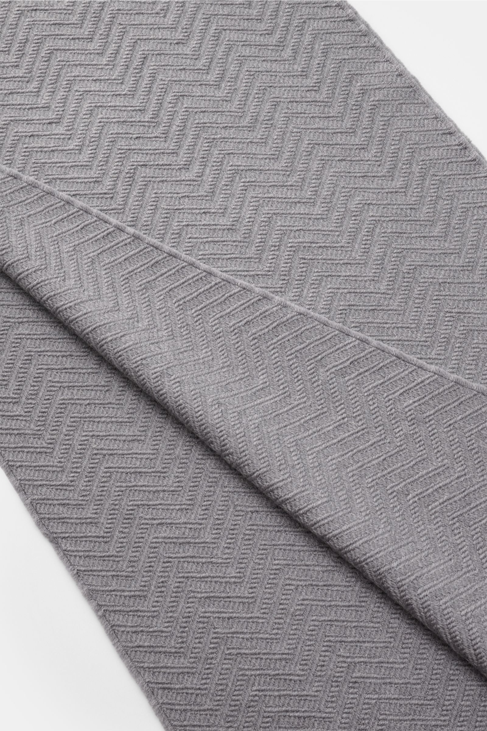 Emporio Armani Schal grau aus reiner Wolle mit tonalem Fischgrat-Muster, Logo-Streifen und schmalem Fransensaum, Draufsicht leicht gefaltet.