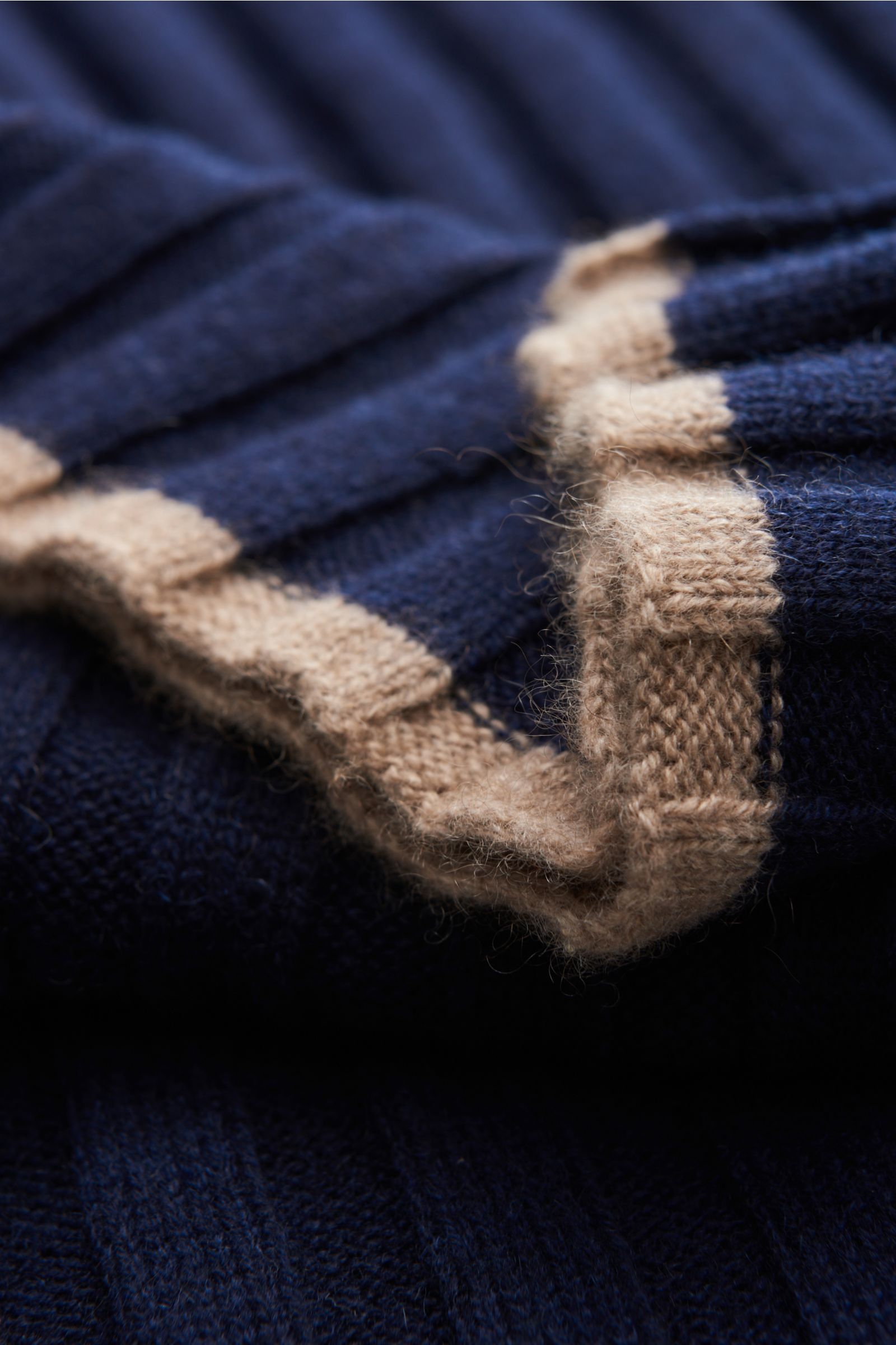 Nahaufnahme aus schräger Perspektive des Brunello Cucinelli Cashmere Schal navy mit breitem Rippstrick, weichem Griff und kontrastfarbigen Kanten.
