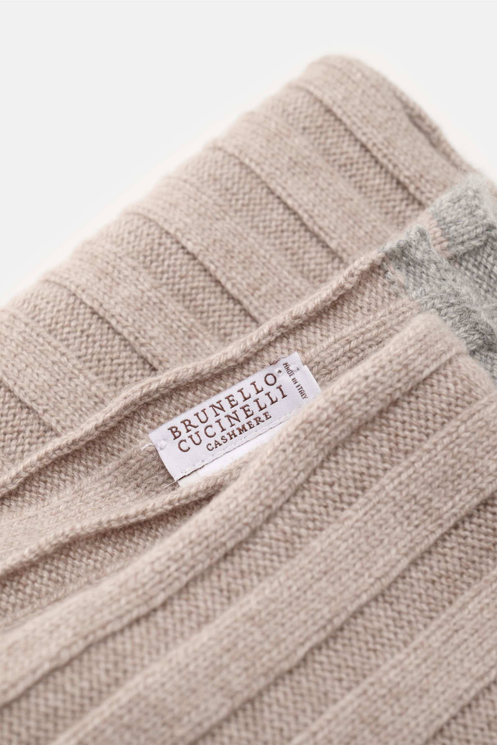 Brunello Cucinelli Cashmere Schal taupe meliert, breiter Rippstrick, weiche Haptik, kontrastfarbige Kante, Detailaufnahme von oben, ca. 155x26 cm.