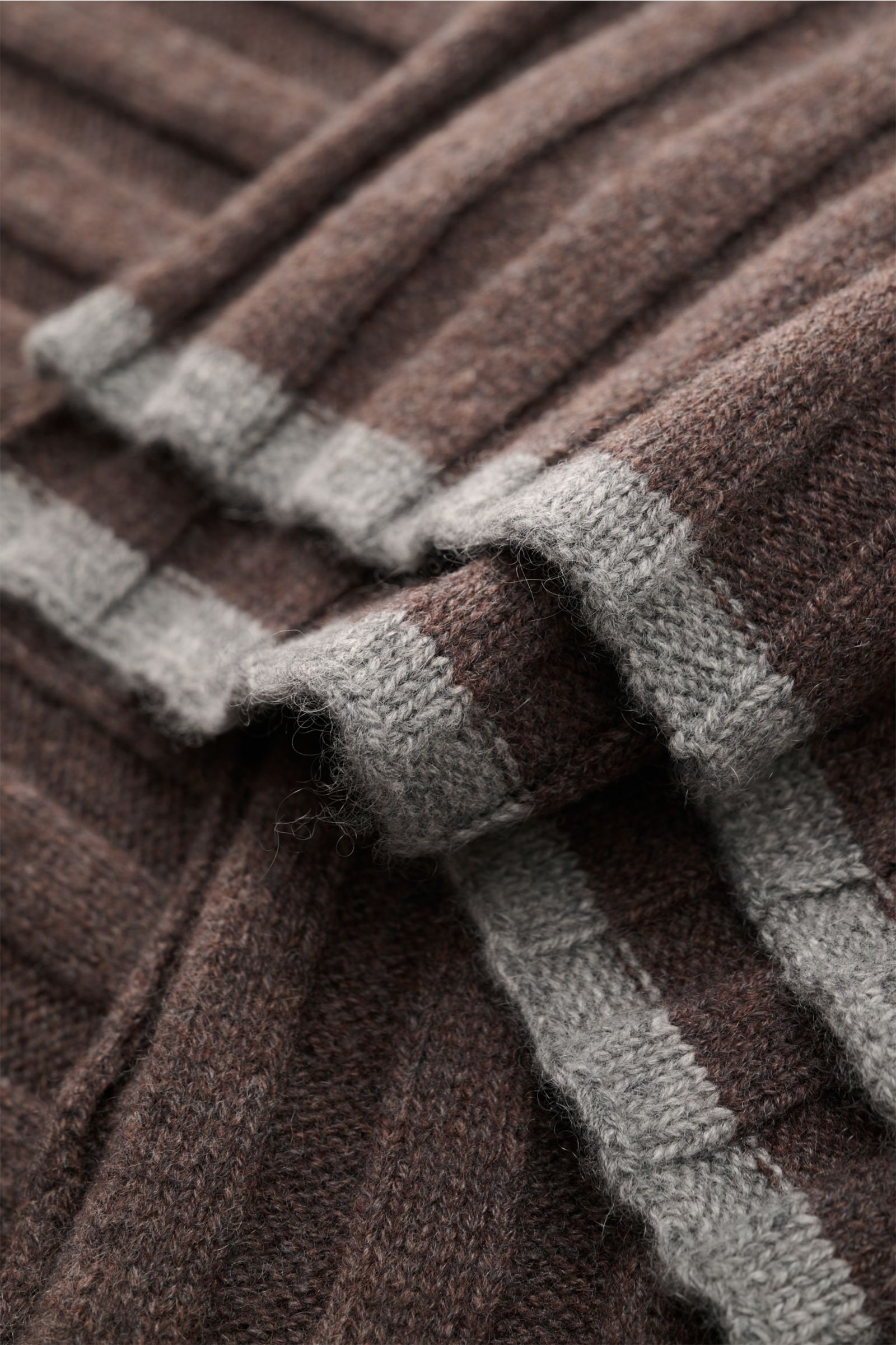 Close-up angled view of the Brunello Cucinelli Cashmere Schal braun meliert, a soft, ribbed brown melange scarf with contrasting light gray edges.

Description: Ein edler Allrounder für die kühle Saison: Dieser Schal von BRUNELLO CUCINELLI aus reinem C