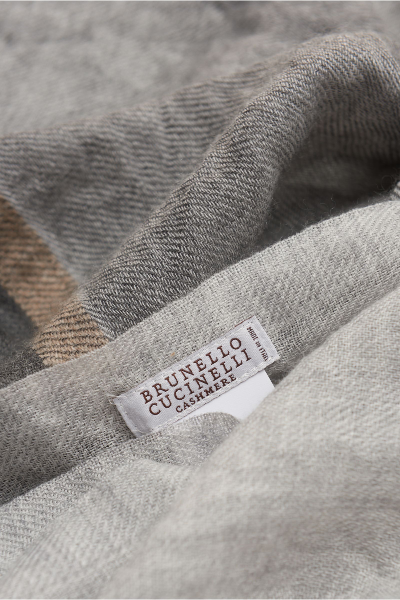 Brunello Cucinelli Schal grau/dunkelgrau in Nahaufnahme von schräg oben, weicher Cashmere-Seide-Mix mit Bicolor-Design, schmalem Fransensaum.
