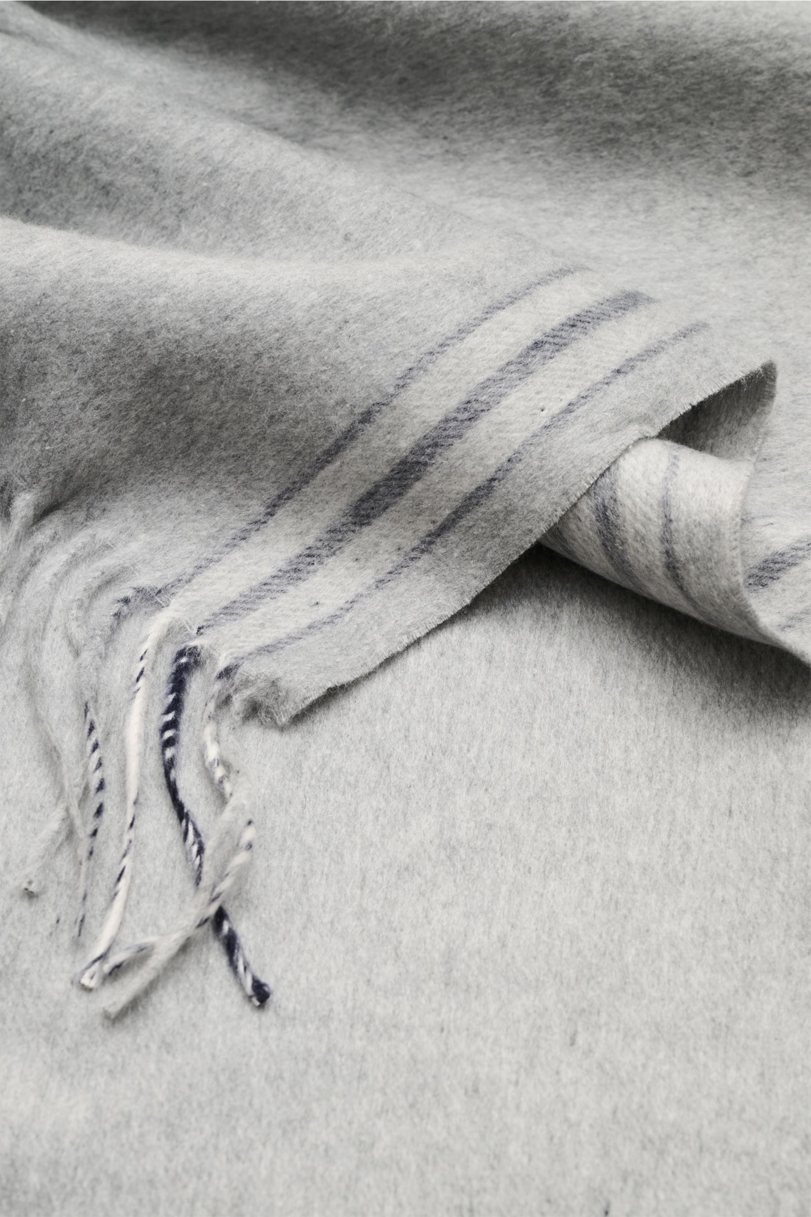 Close-up, angled top view of the Brunello Cucinelli Seidenschal navy/grau/bordeaux showing reine Seide, very soft texture, schmale Kontraststreifen, Saum mit Fransen, Maße: ca. 155 cm x 48 cm.