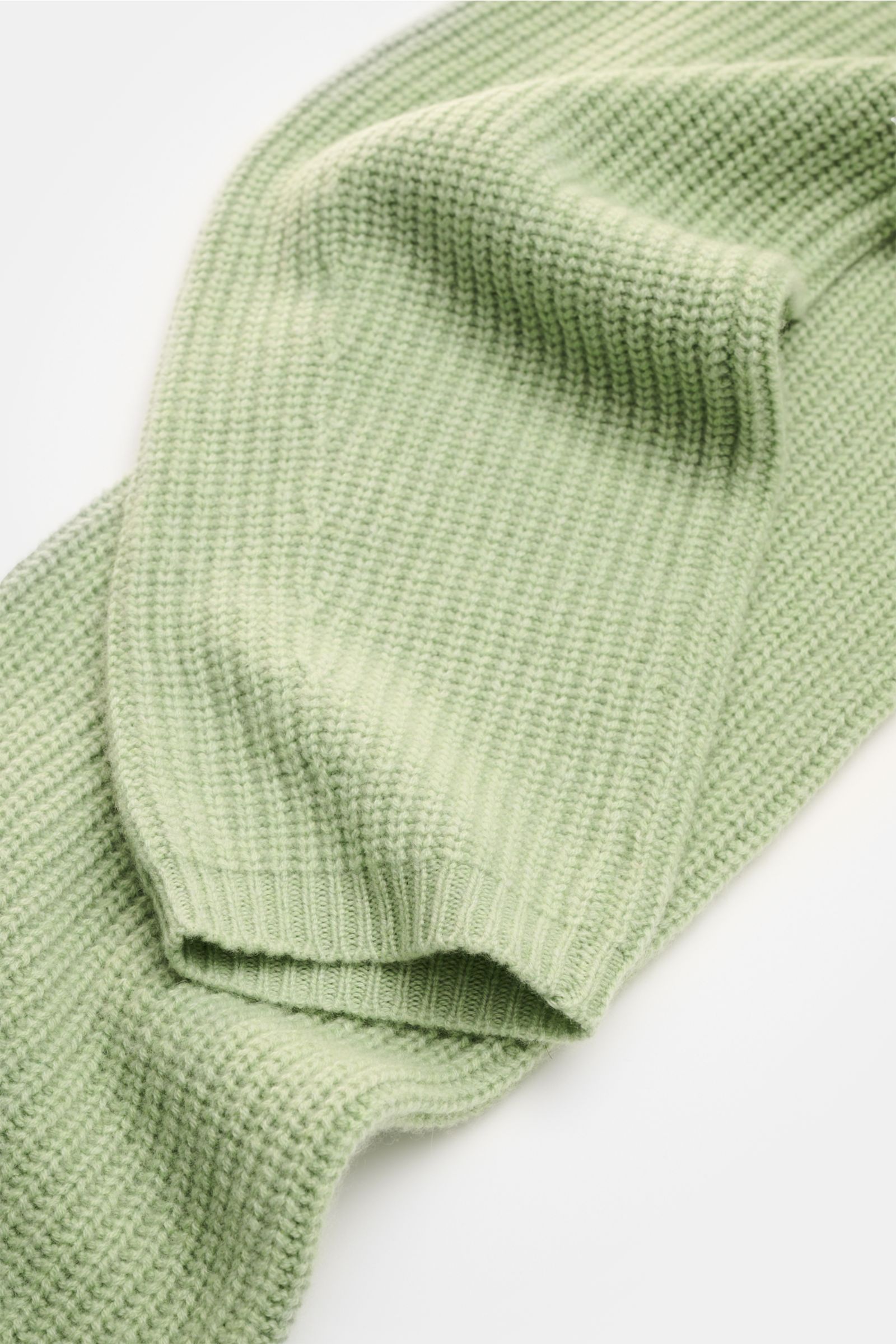 Close-up top-down view of the Lisa Yang Cashmere scarf 'Marseille' light green showing its voluminous ribbed texture and open rib knit cuffs.

A luxurious accessory: The scarf 'Marseille' in voluminous cashmere from Swedish label LISA YANG has a distin