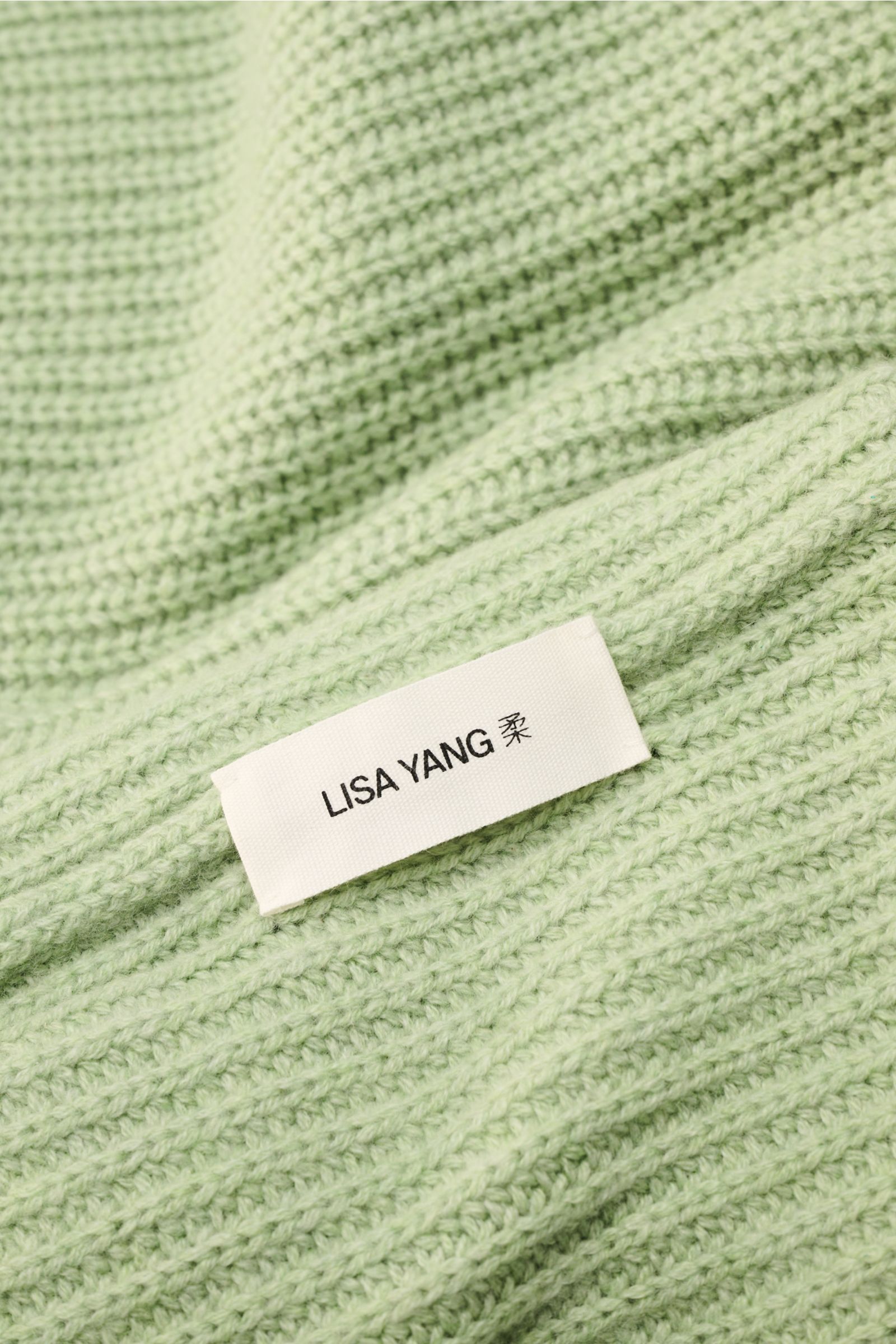 Close-up front view of Lisa Yang Cashmere scarf 'Marseille' light green showing its ribbed texture and white brand label.

Description:  
A luxurious accessory: The scarf 'Marseille' in voluminous cashmere from Swedish label LISA YANG has a distinctive