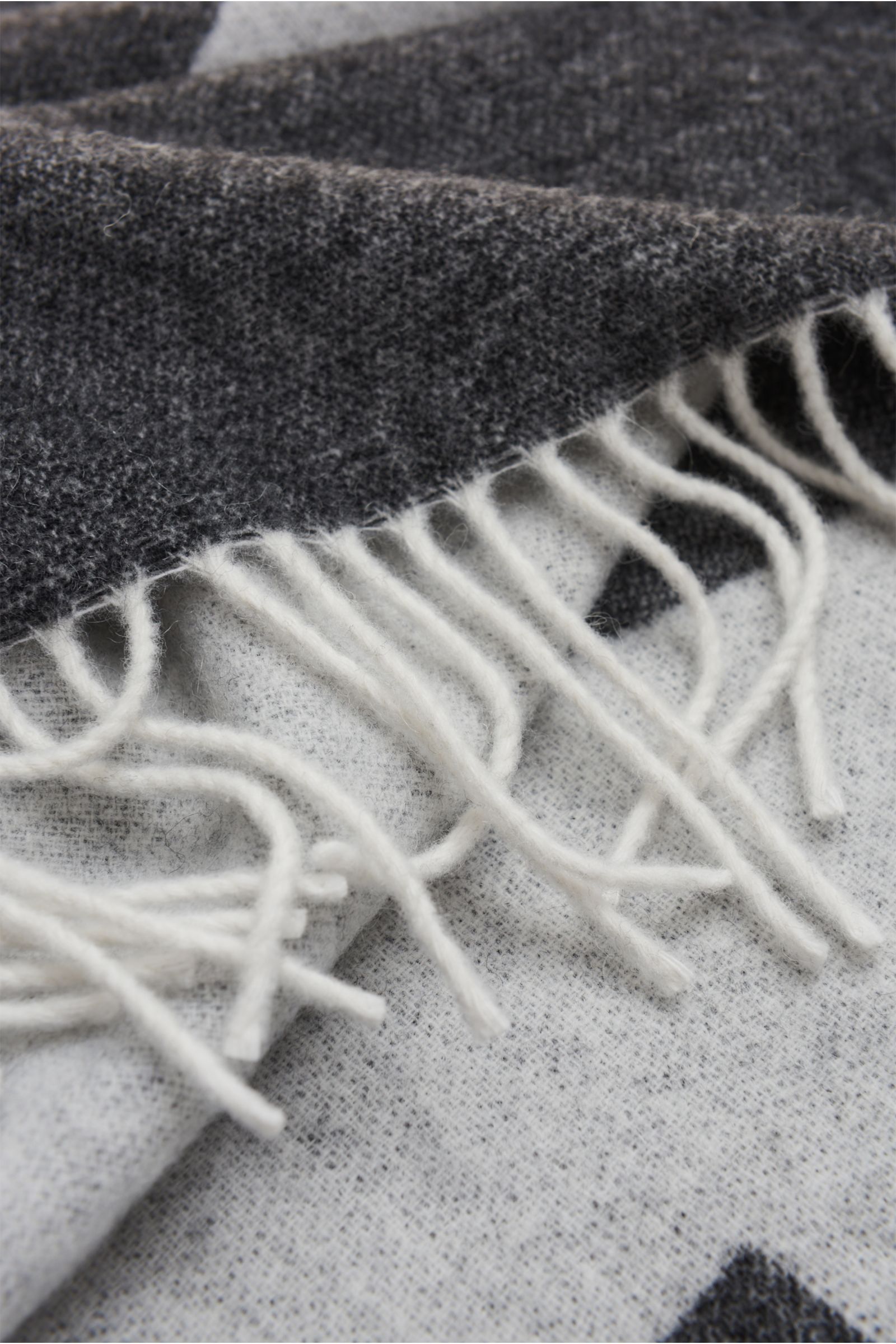 Nahaufnahme des A.P.C. Schal schwarz/offwhite mit weichem Griff, Doubleface-Design, Fransen, großflächigem Logo, aus Wolle und Microfaser, ca. 205x38 cm.