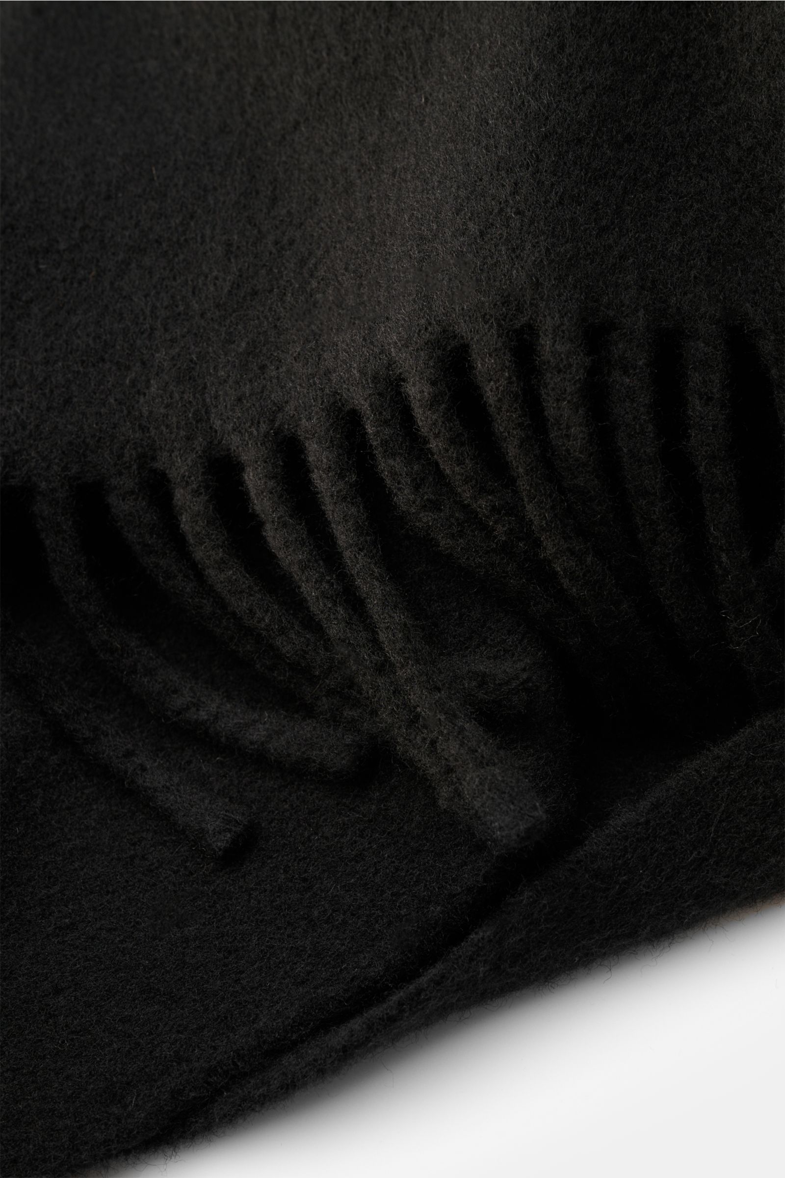 Ami Paris Schal schwarz aus gewalkter Wolle mit weichem Griff, beidseitiger Fransenkante und erhabenem 'Ami de Cœur'-Logo, Nahaufnahme von schräg oben.