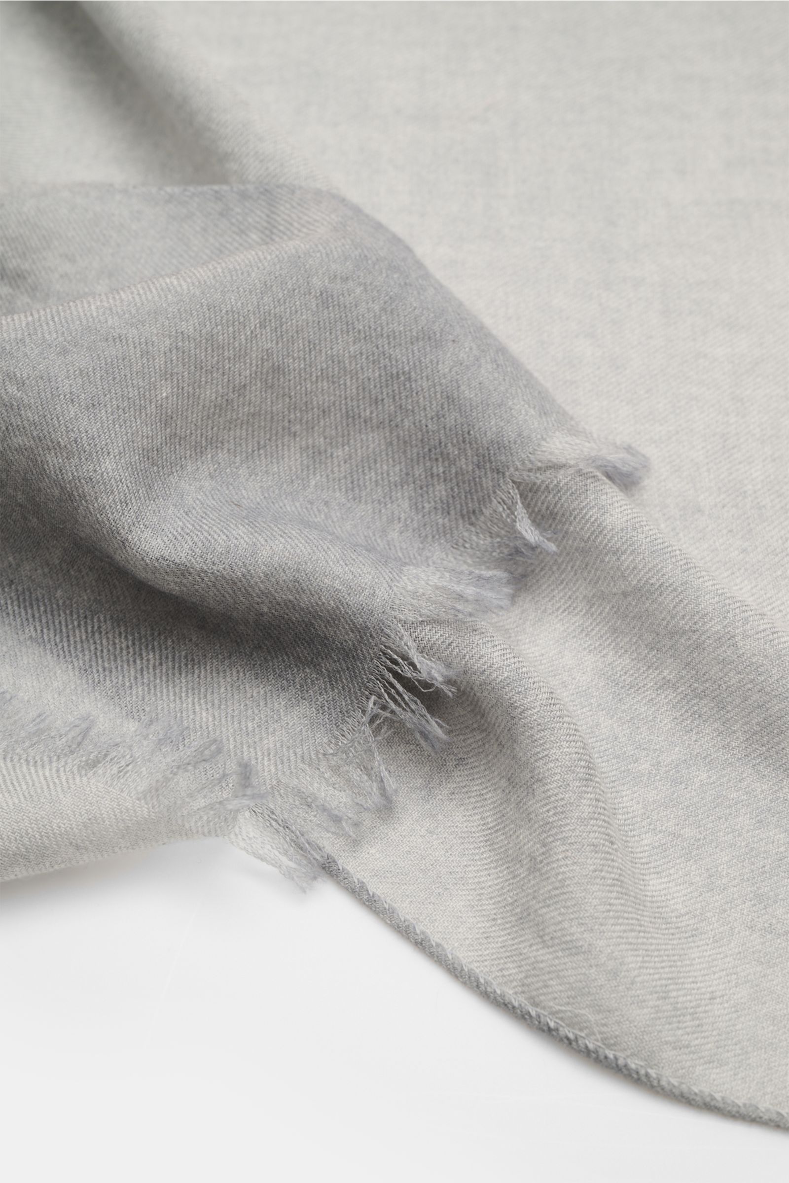 Colombo Scarf grey photographed from an angled close-up showing fine cashmere and silk blend, soft feel, lightweight fabric, narrow fringed edges, dimensions approx. 196 cm x 70 cm.
