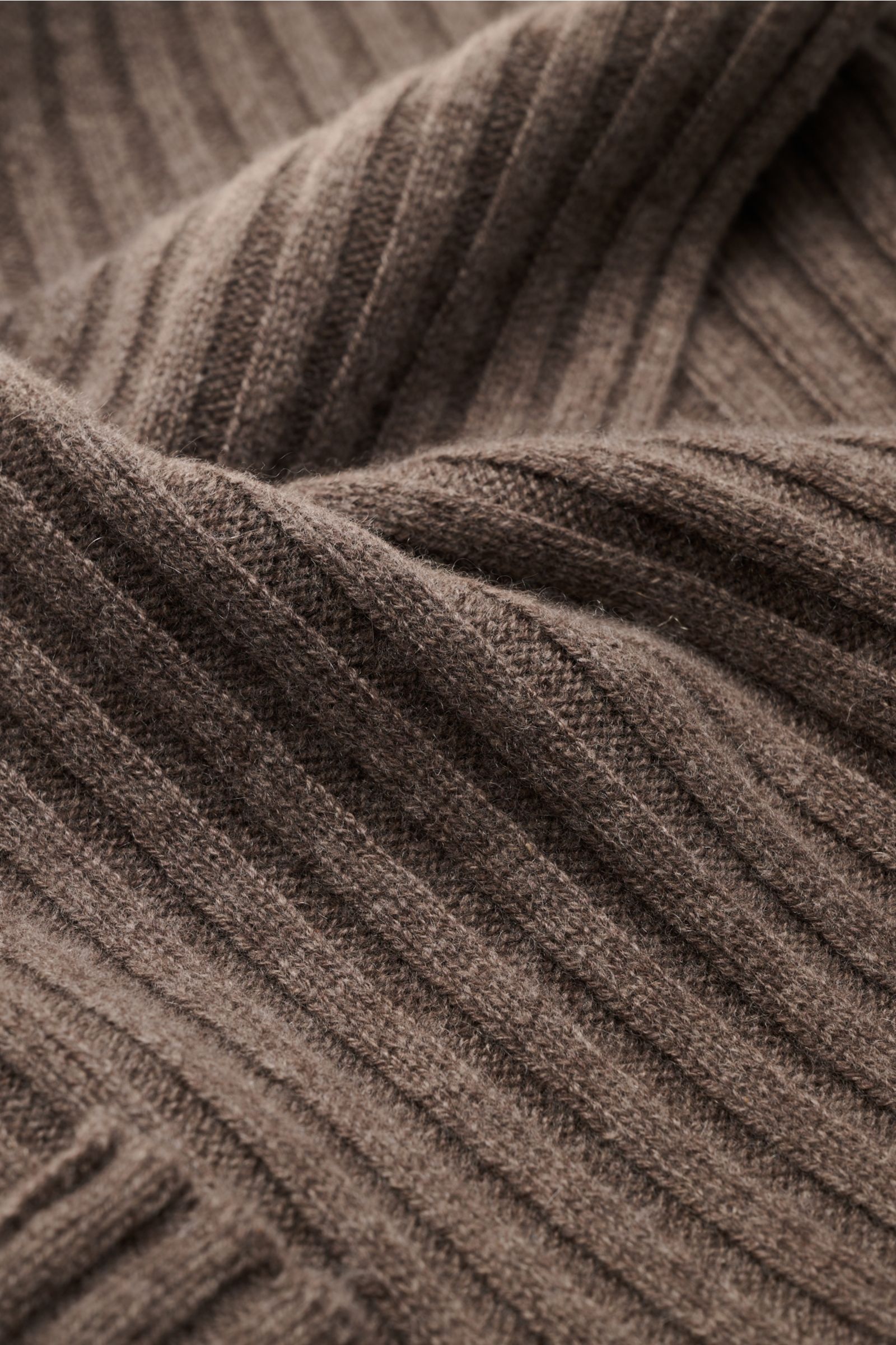 Nahaufnahme aus schräger Perspektive eines FTC Cashmere Schal graubraun mit breitem Rippstrickmuster, weichem Griff und großem Weblabel.