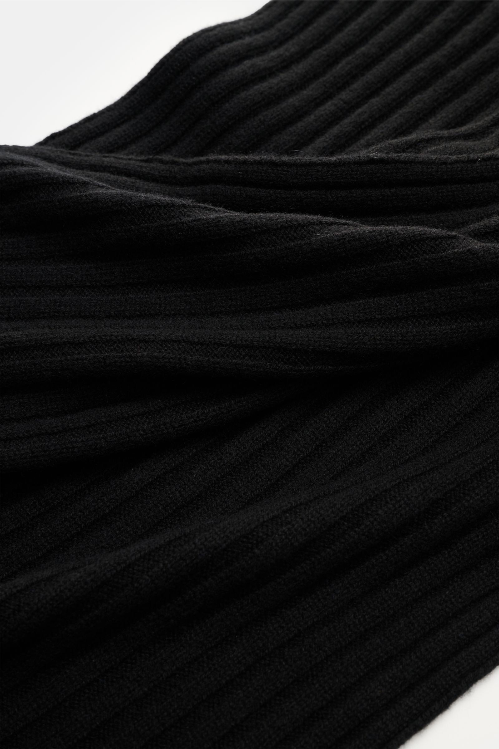 Nahaufnahme des FTC Cashmere Schal schwarz mit breitem Rippstrickmuster und großem Weblabel, aus reinem Fair Trade Cashmere.