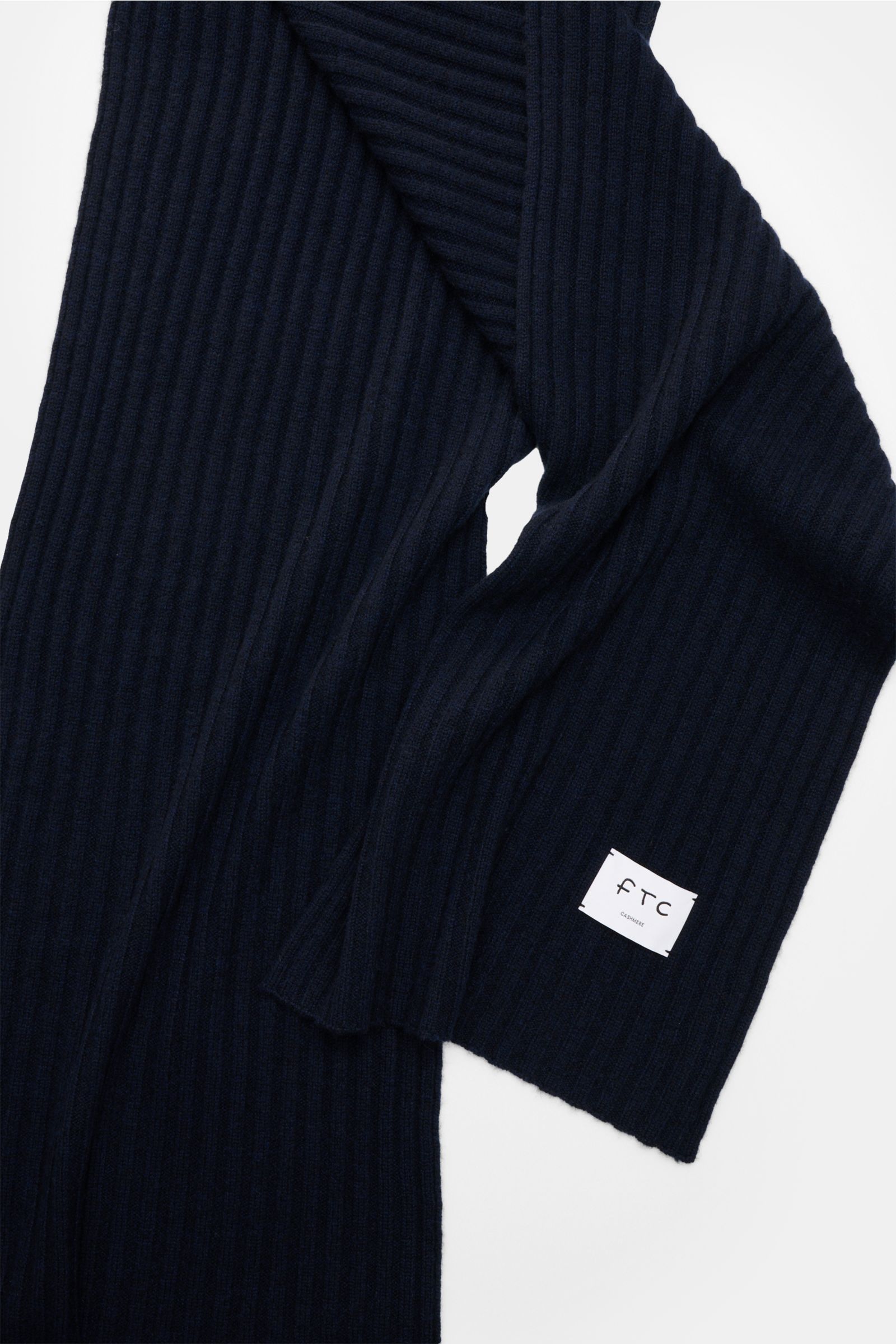 FTC Cashmere Schal navy aus reiner Fair Trade Cashmere, weicher Griff, breites Rippstrickmuster, großes Weblabel, frontale Nahaufnahme.