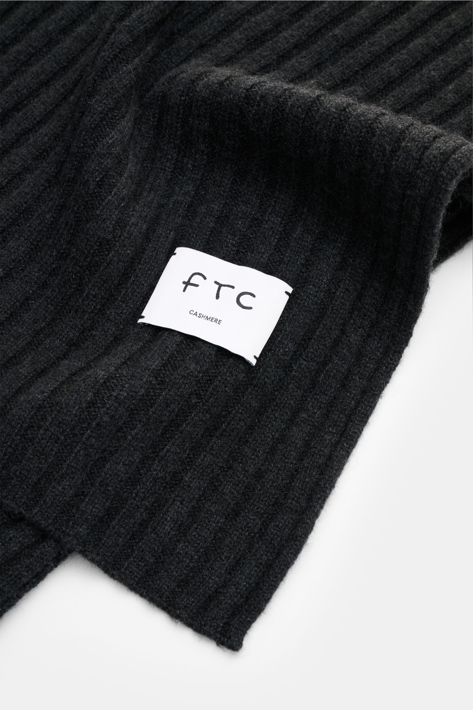 FTC Cashmere Schal dunkelgrau aus reinem Fair Trade Cashmere mit weichem Griff, breitem Rippstrickmuster und großem Logo-Label, Nahaufnahme.