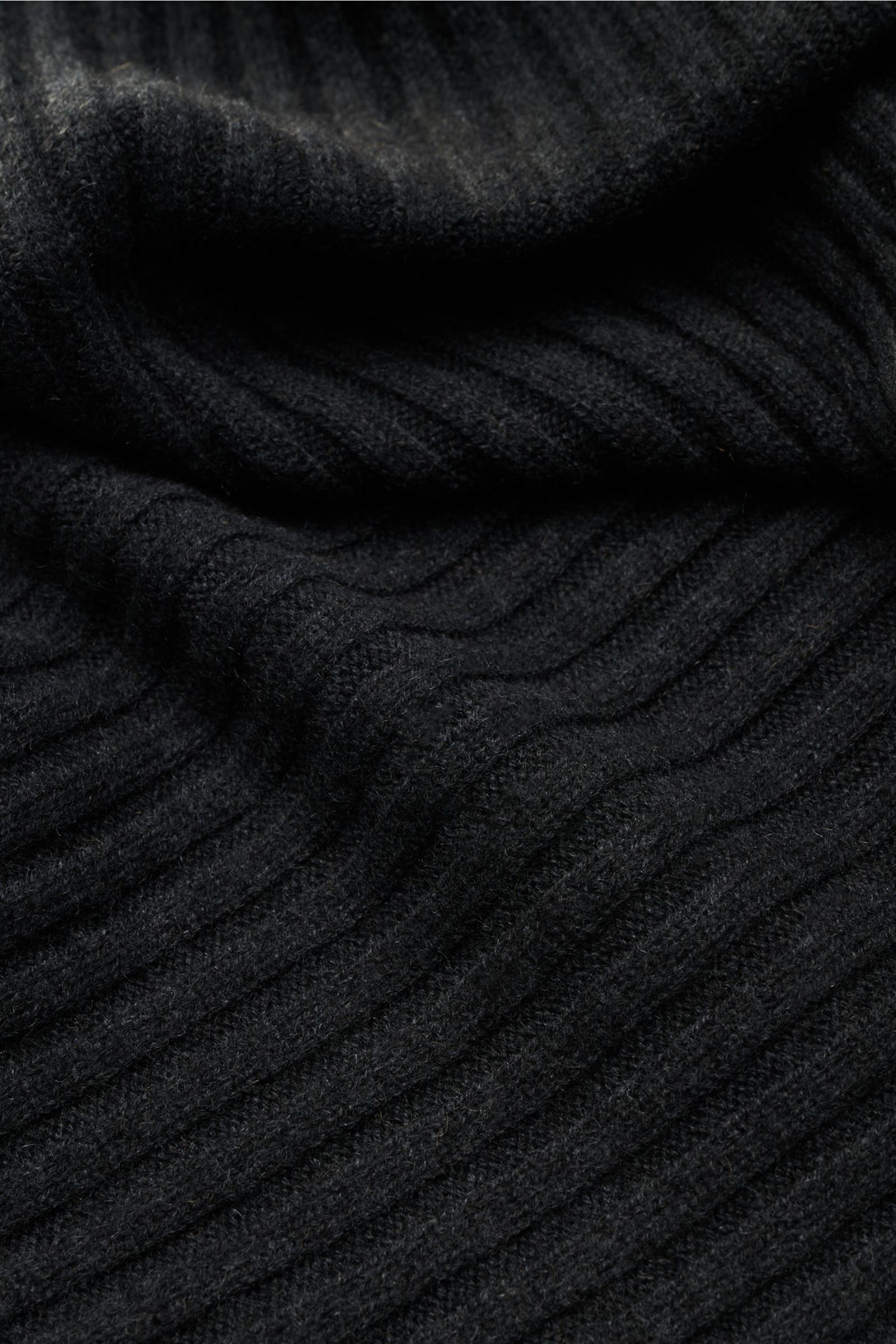 FTC Cashmere Schal dunkelgrau aus reinem Fair Trade Cashmere mit breitem Rippstrickmuster, weichem Griff, großem Weblabel, Nahaufnahme seitlich.