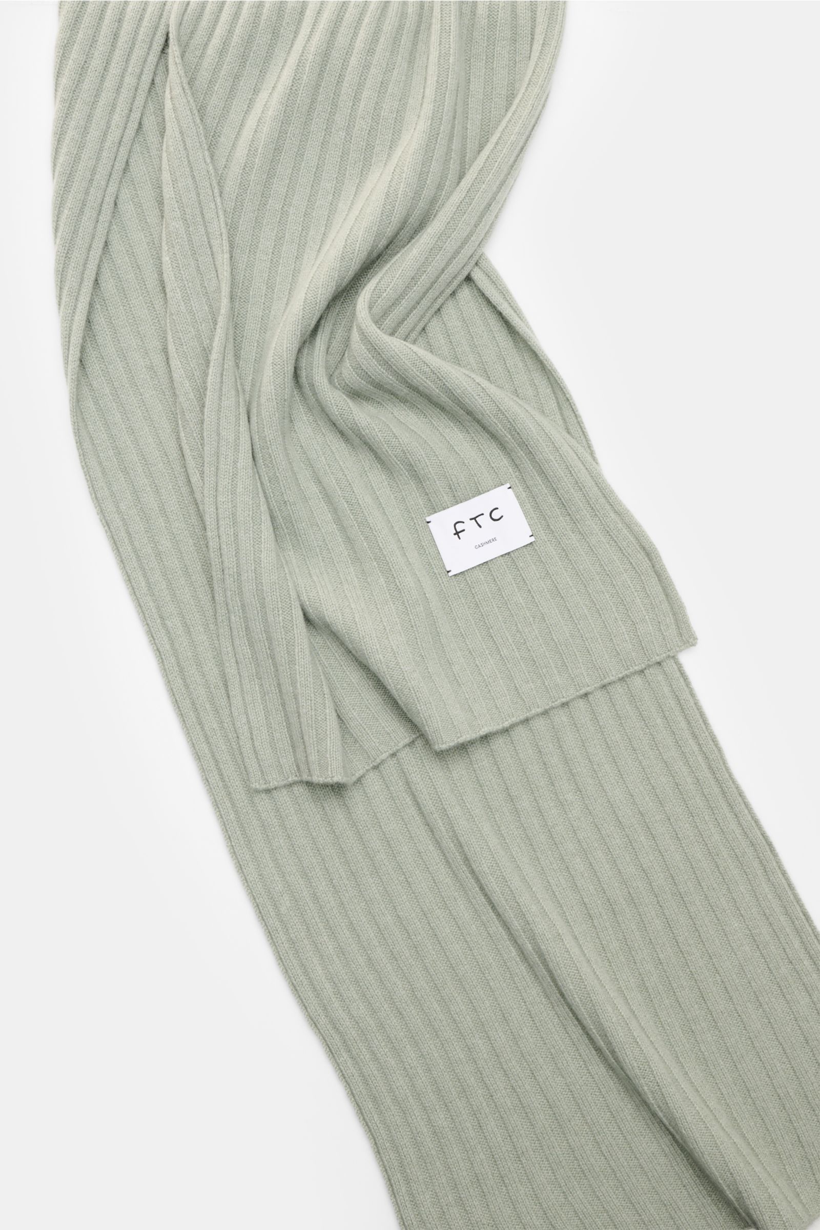 FTC Cashmere Schal graugrün aus reinem Fair Trade Cashmere mit breitem Rippstrickmuster und großem Weblabel, liegend fotografiert.