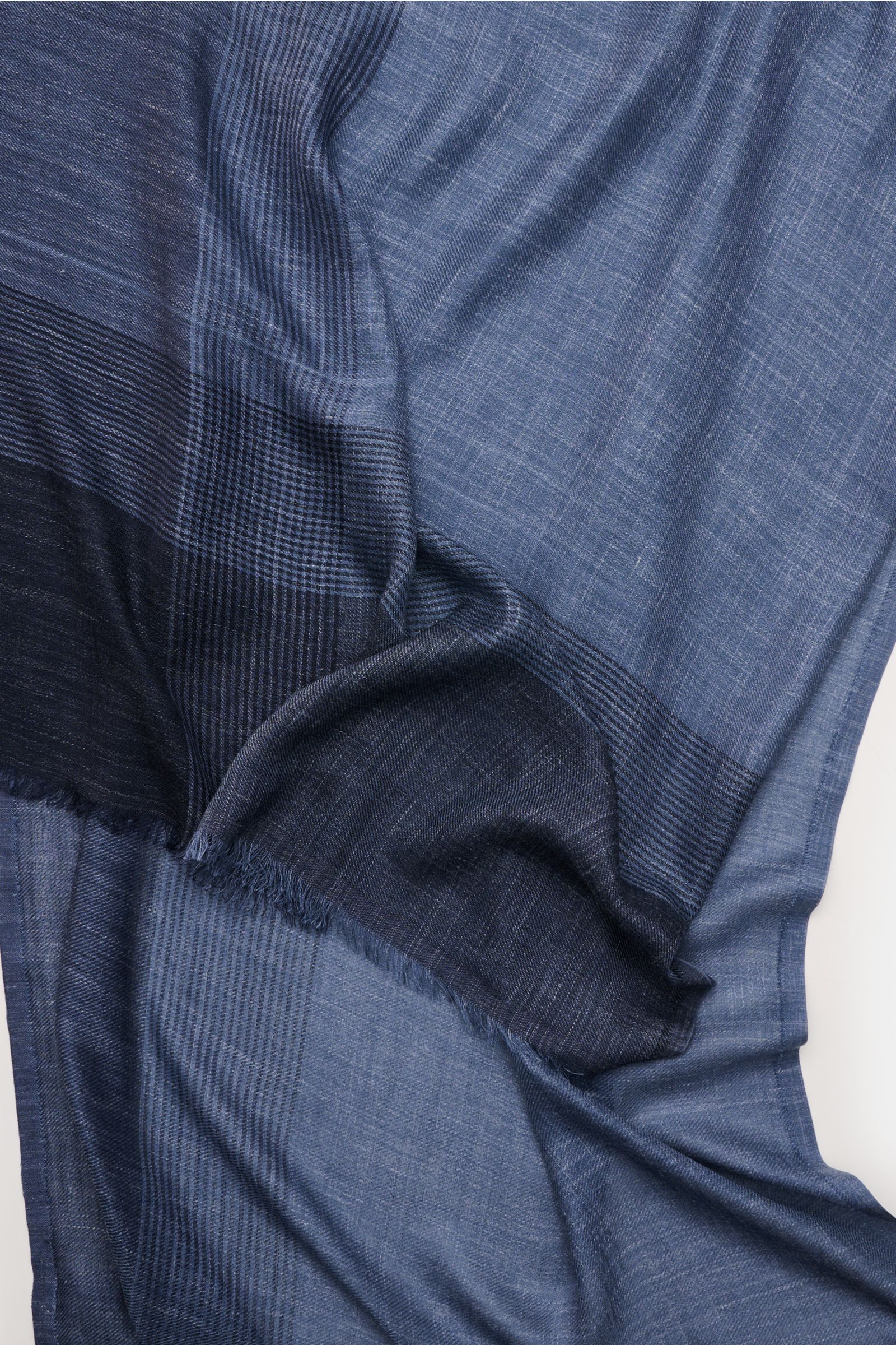 Close-up top view of the Brunello Cucinelli Schal graublau/navy kariert showing its soft silk and linen blend with a subtle plaid pattern and narrow fringed edges.

Additional description: 
Das Quiet-Luxury-Label BRUNELLO CUCINELLI ist bekannt für sein