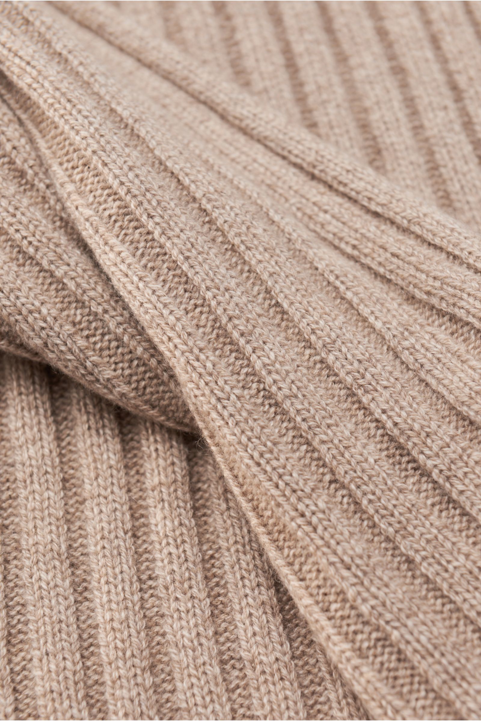 Nahaufnahme aus schräger Perspektive des von Braun Cashmere Schal beige meliert mit klassischem Rippstrick-Design, feinem Strickbild und weichem Griff.