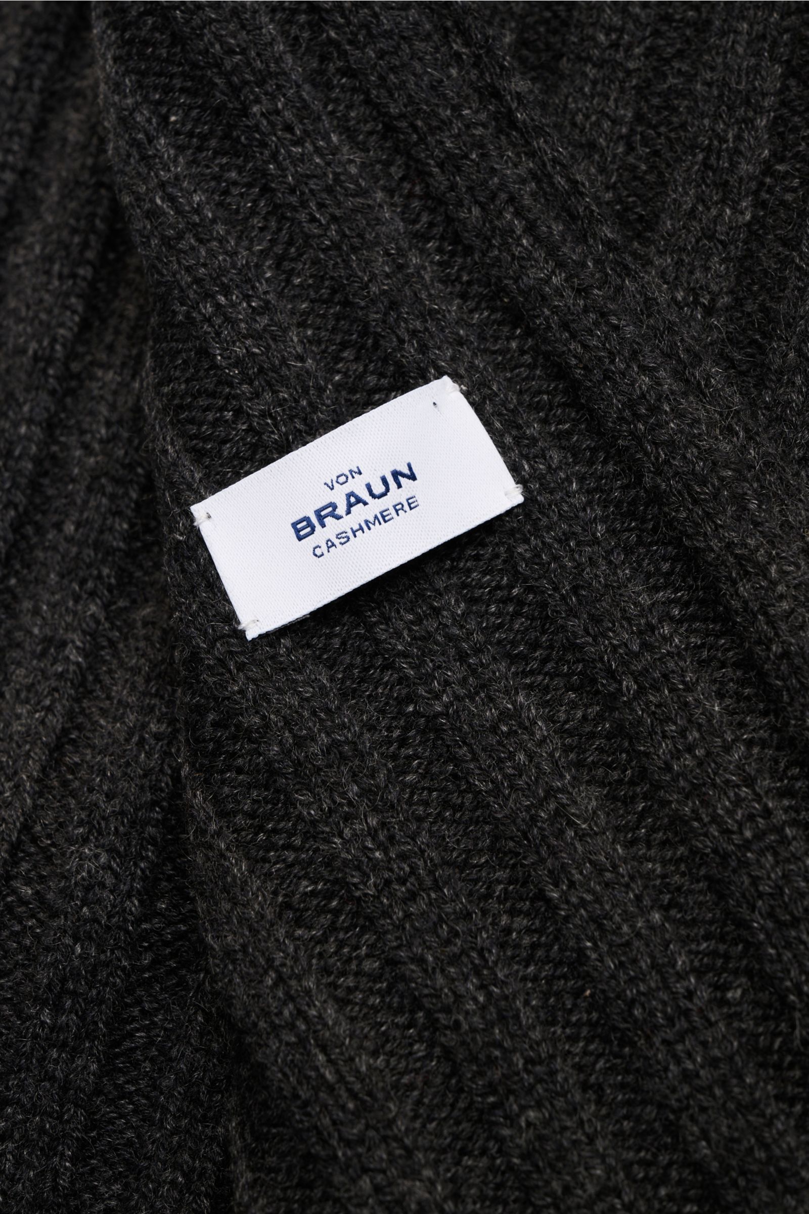 Nahaufnahme des von Braun Cashmere Schal anthrazit meliert mit feinem Rippstrick-Design und weißem Markenlabel, reiner Cashmere, weich.