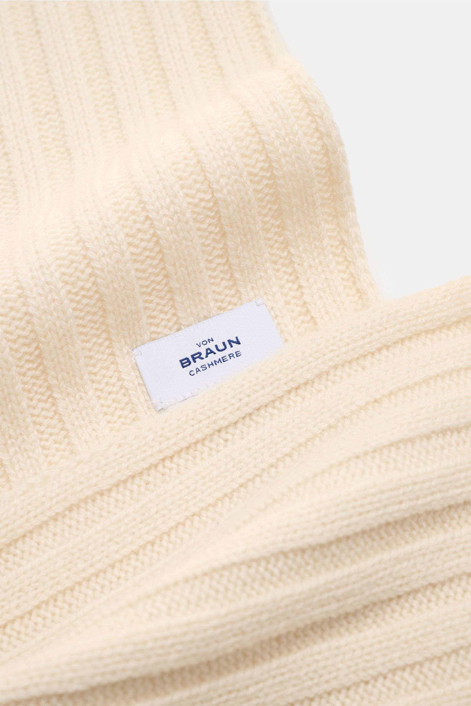 Nahaufnahme des von Braun Cashmere Schal offwhite mit klassischem Rippstrick-Design und Markenlabel, weich, 169x25 cm.