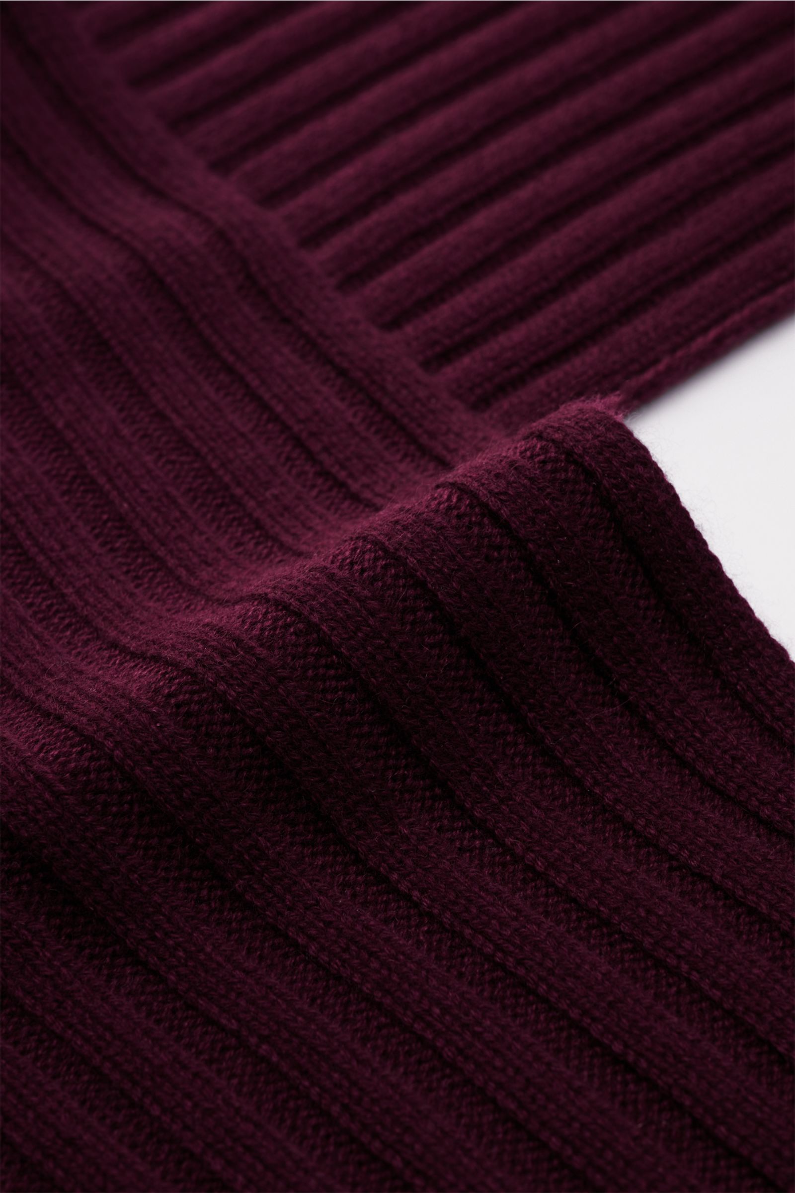 Nahaufnahme des von Braun Cashmere Schal bordeaux in klassischem Rippstrick-Design, weicher Griff, feines Strickbild, seitliche Perspektive.