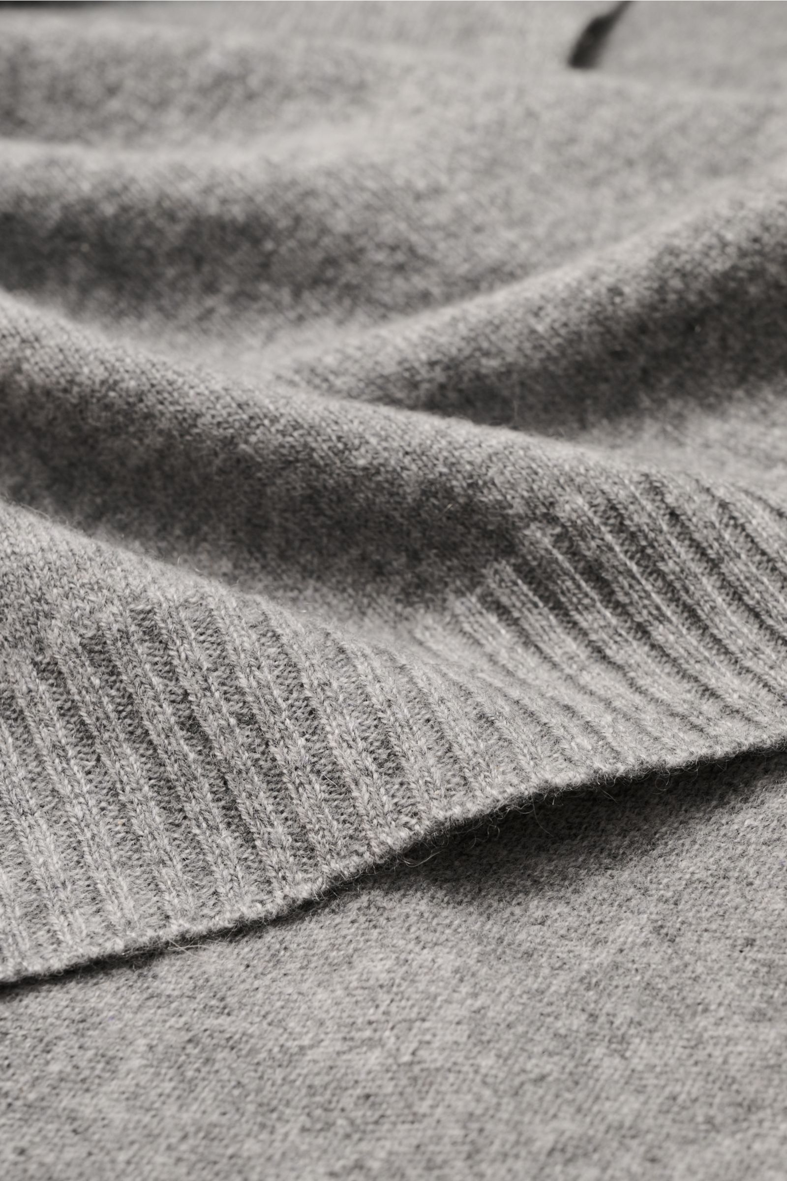 Nahaufnahme des cremefarbenen 04651/ A trip in a bag Cashmere Schals mit weichem Griff und Rippstrick-Kanten, perspektivisch von oben fotografiert.