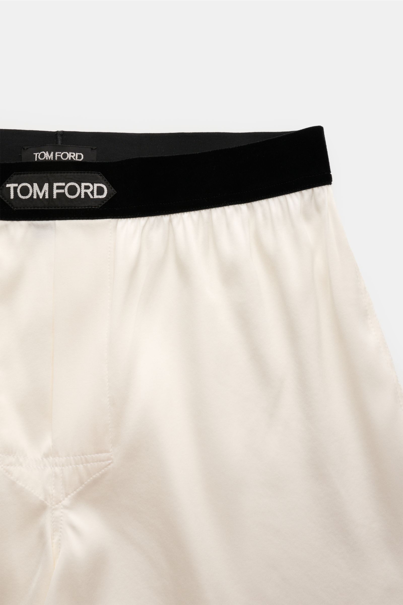 Close-up front view of Tom Ford Seiden-Boxershorts offwhite with black elastic velvet waistband and logo label, made from luxurious silk with stretch, slim fit, soft smooth touch, and side fly for maximum comfort. Luxus, der auf der Haut beginnt: Diese