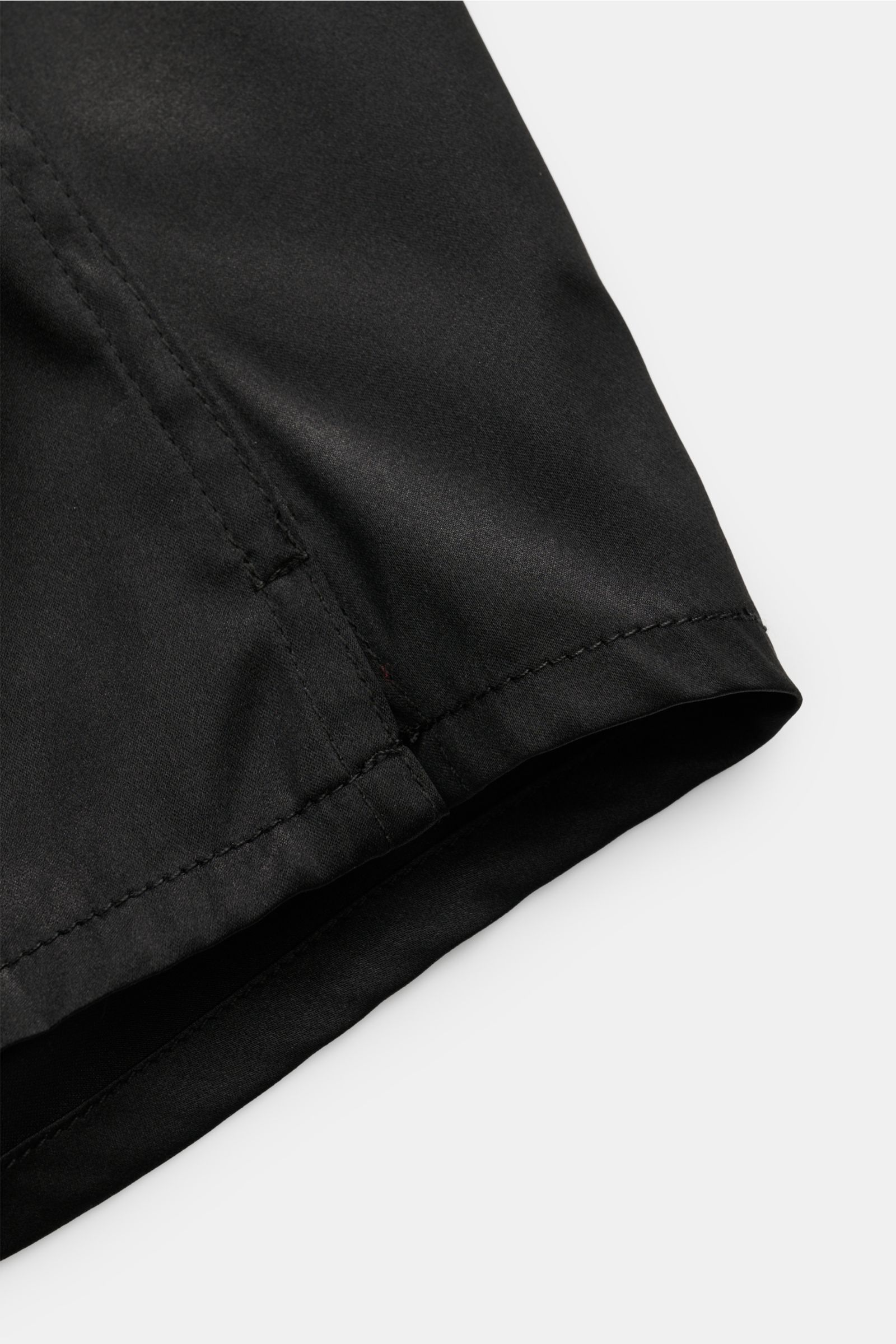 Close-up side view of Tom Ford Seiden-Boxershorts schwarz showing smooth black silk fabric with fine stitching and slim fit design, featuring a soft elastic velvet waistband with logo label for comfort. Luxus, der auf der Haut beginnt: Diese Boxershorts v