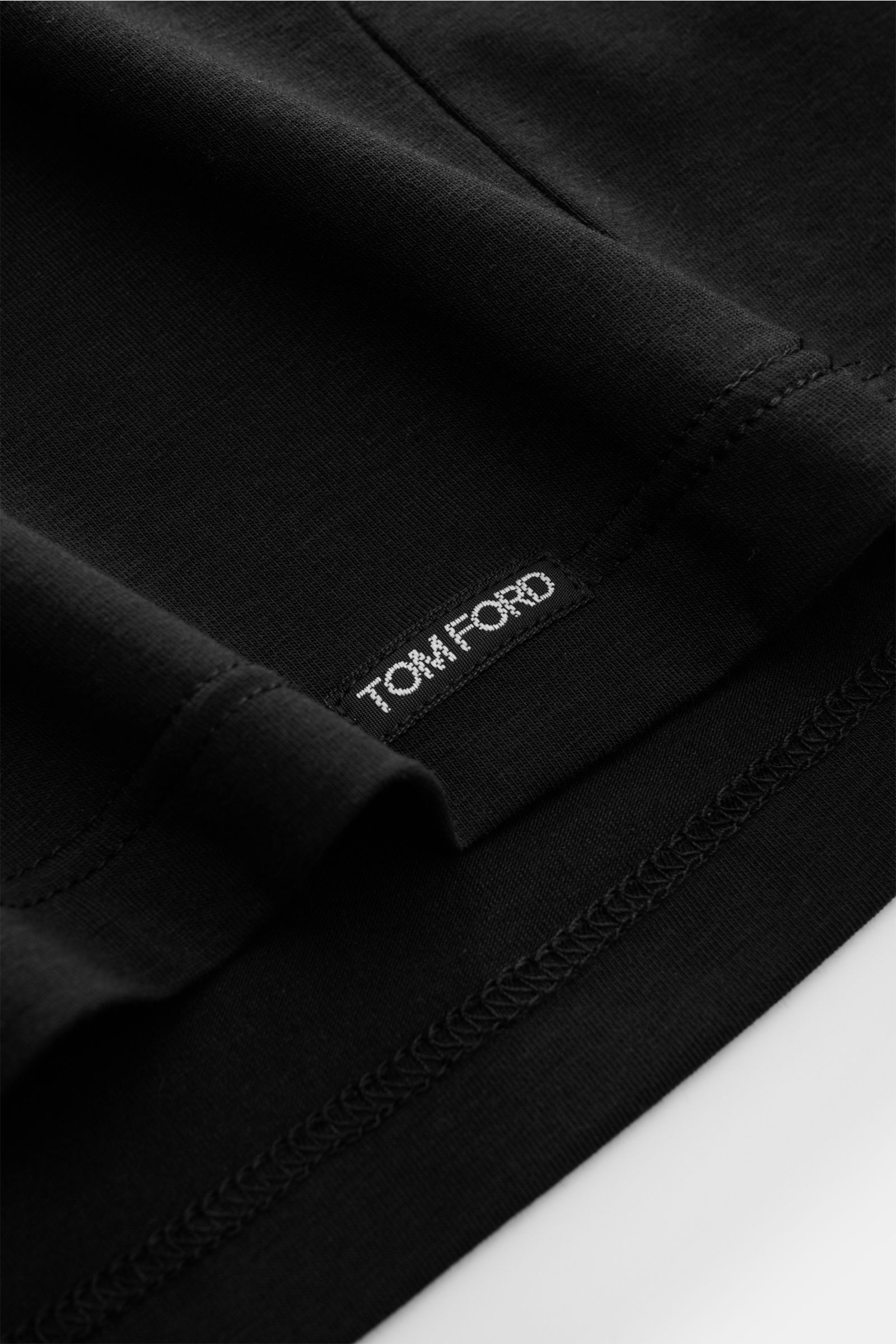 Close-up shot of the Tom Ford Rundhals-Unterhemd schwarz showing fine stitching and small TOM FORD label at the hem.

Description: Cleanes Basic mit Rundhalsausschnitt: Das komfortable T-Shirt aus hochwertiger Baumwoll-Modal-Mischung vom Luxus-Label TO