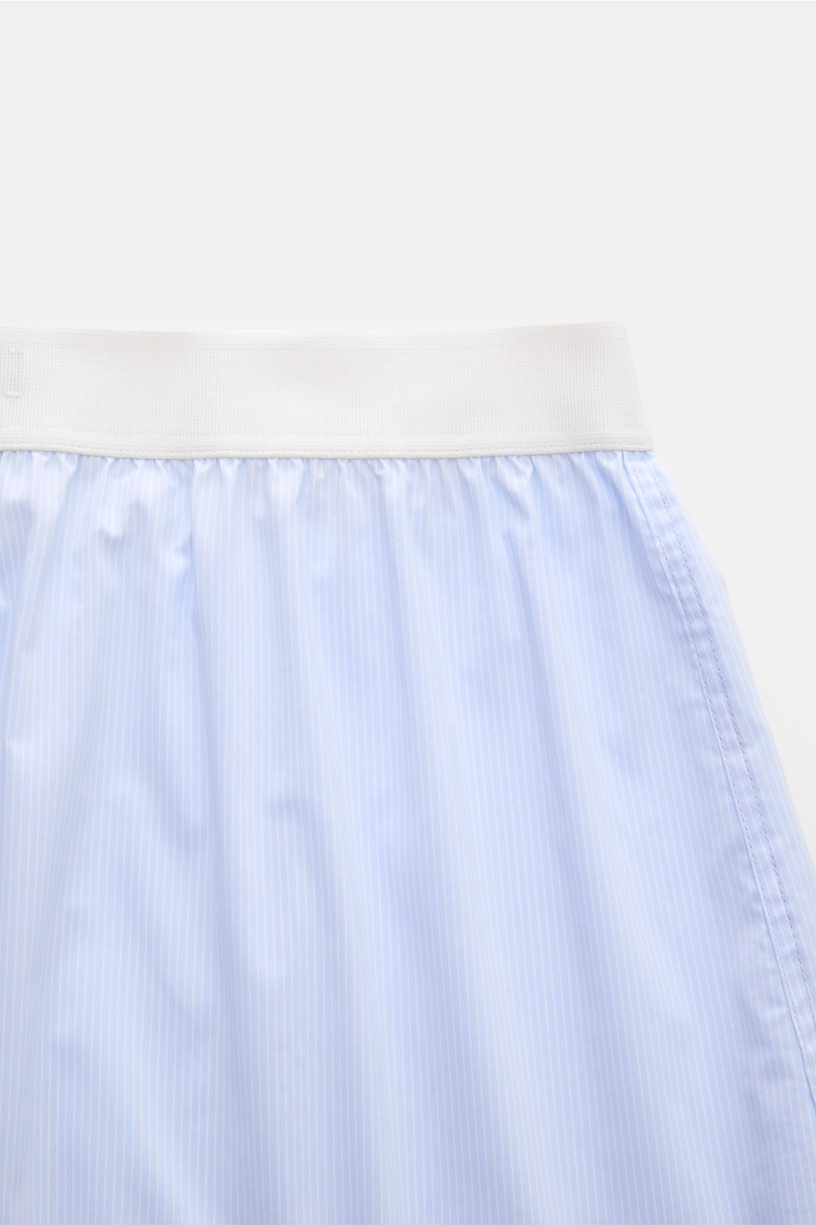 Close-up front view of Tom Ford Boxershorts hellblau/weiß gestreift featuring a slim fit, fine blue and white stripes, elastic white waistband with TOM FORD logo, and side opening. Sportlich, clean und luxuriös: Diese Boxershorts präsentieren sich im fein
