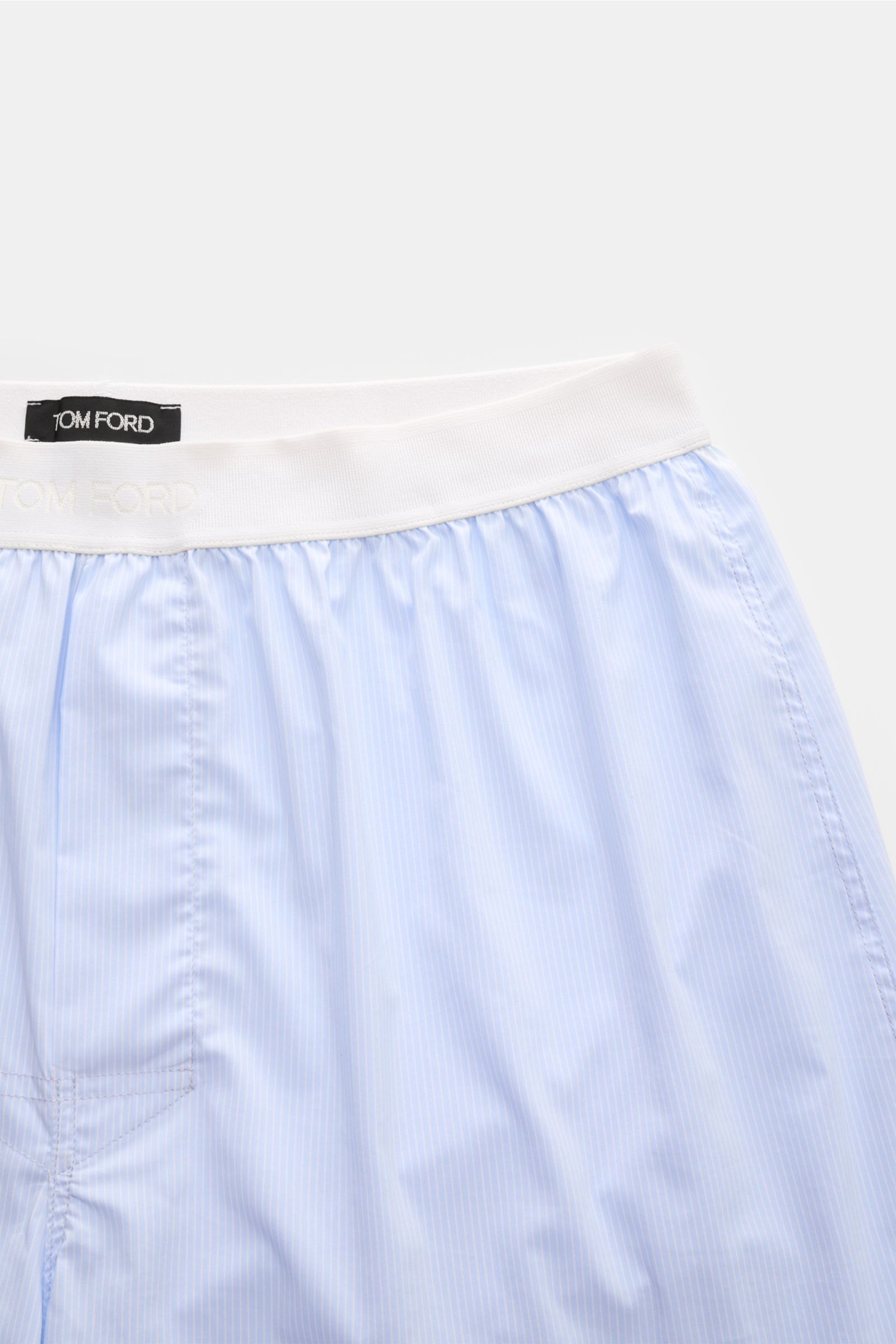 Close-up top view of Tom Ford Boxershorts hellblau/weiß gestreift showing fine stripes, elastic waistband with logo, and smooth cotton blend fabric. Sportlich, clean und luxuriös: Diese Boxershorts präsentieren sich im feinen Streifenmuster und überzeugen