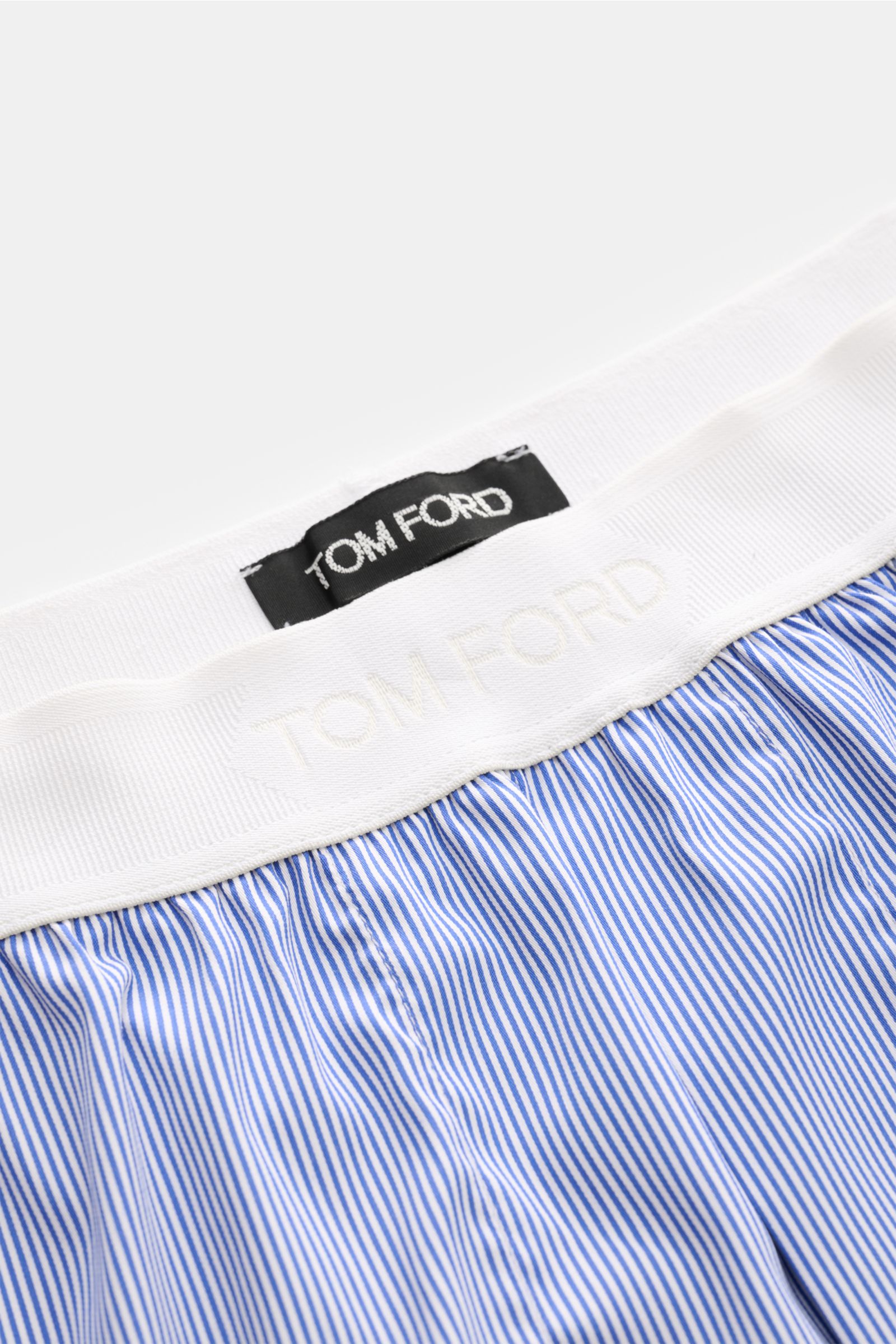 Close-up top view of Tom Ford Boxershorts dunkelblau/weiß gestreift with white elastic waistband, fine blue and white stripes, and TOM FORD logo.

Description to include: Sportlich, clean und luxuriös: Diese Boxershorts präsentieren sich im feinen Streife