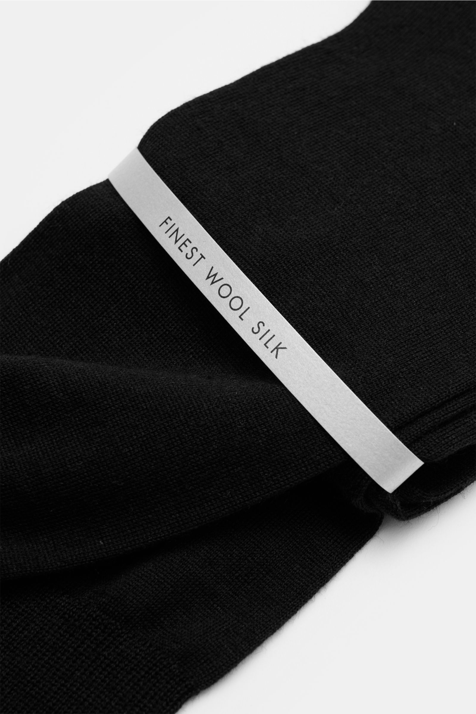 Close-up angled view of folded black Falke Strumpf 'No. 7' schwarz socks with a 'Finest Wool Silk' label, showing fine texture.

Optimale Passform, luxuriöse Materialqualität, FALKE: Der Strumpf 'No. 7' des Traditionslabels garantiert durch feinste two