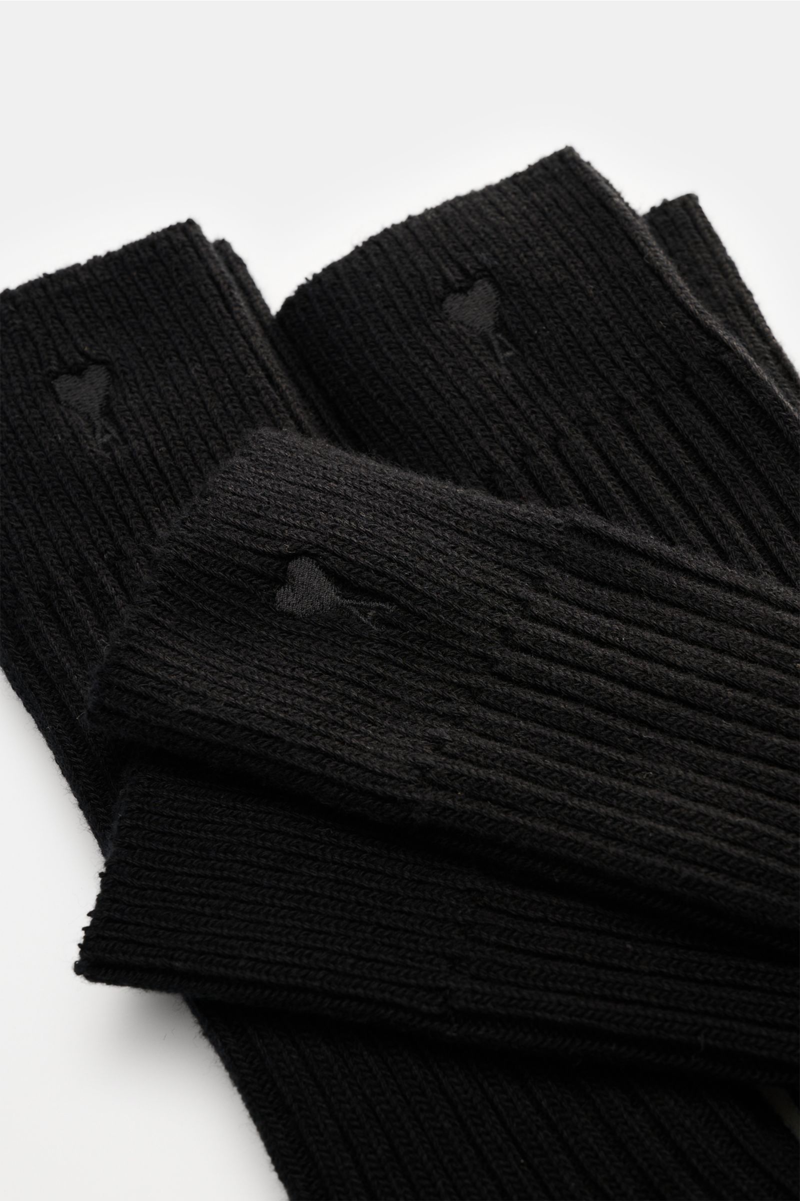 Close-up top-down view of Ami Paris Strümpfe 3er-Set schwarz, ribbed black socks with heart stitching and wide cuffs.

Vom Basic zum Statement mit Herzensangelegenheit schaffen es die Strümpfe im 3er-Set von AMI PARIS, die das französische Label mit se