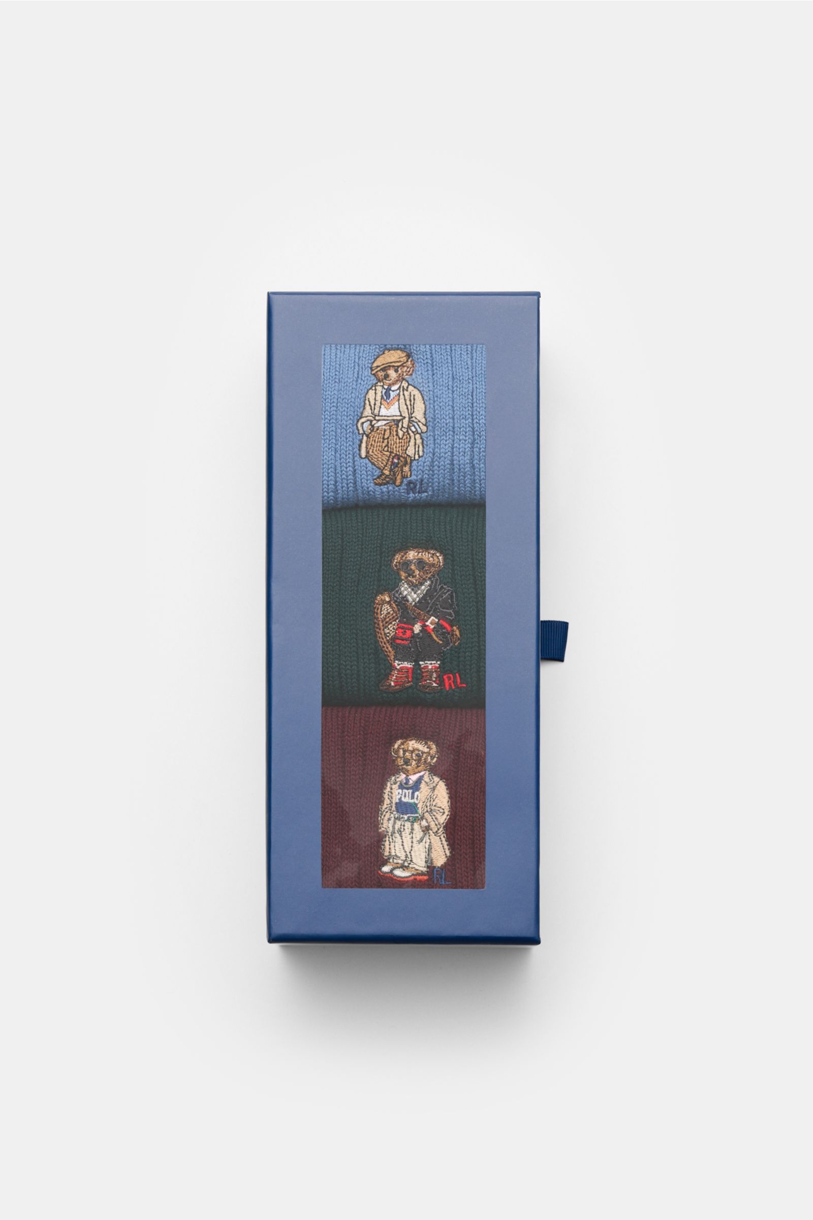 Top-down view of Polo Ralph Lauren Strümpfe 3er-Set rauchblau/dunkelgrün/bordeaux in a blue box, showing three ribbed socks with teddy bear embroidery.

Stylishe Statements für die kalte Jahreszeit: Die Strümpfe mit dem charakteristischen POLO RALPH LA