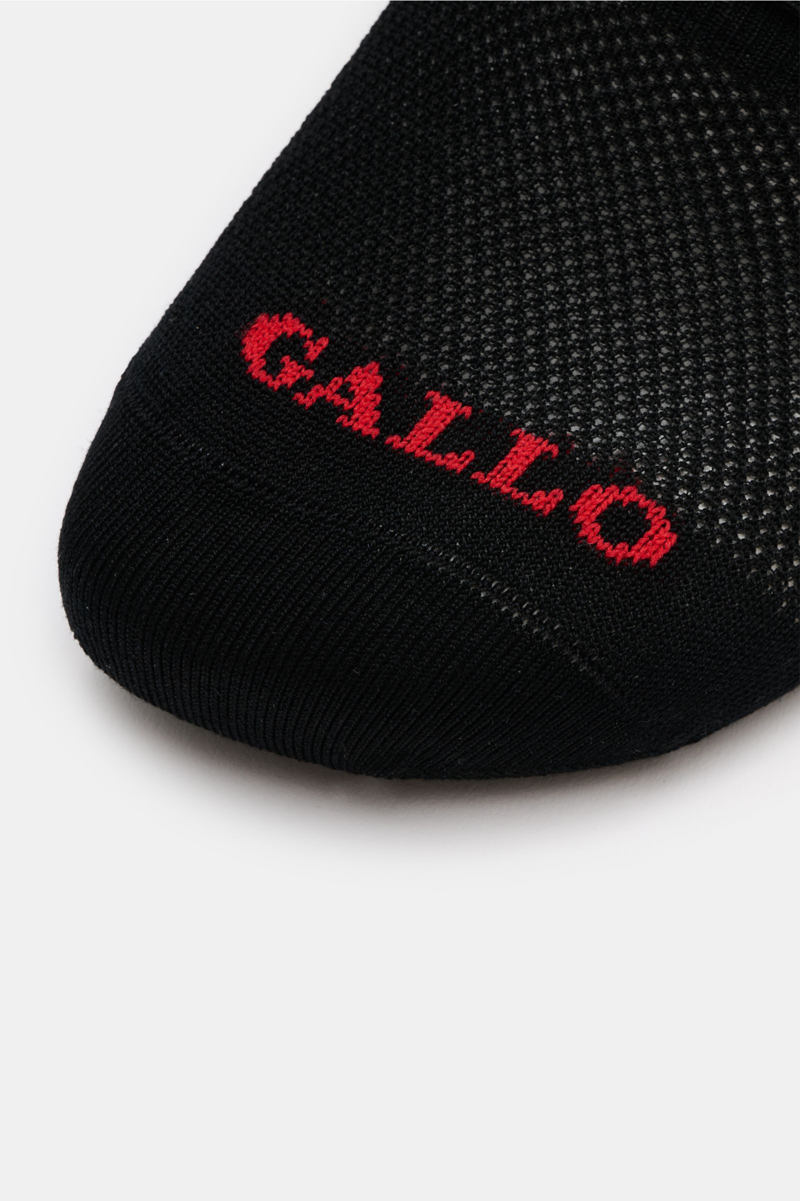 Close-up front view of the Gallo Strumpf anthrazit sock showing fine knit texture and red 'GALLO' logo on black fabric.  
Ein eleganter Schuh kombiniert mit einem hochwertigen Strumpf aus extrafeiner Merinowolle und Microfaser von GALLO ergibt die perf