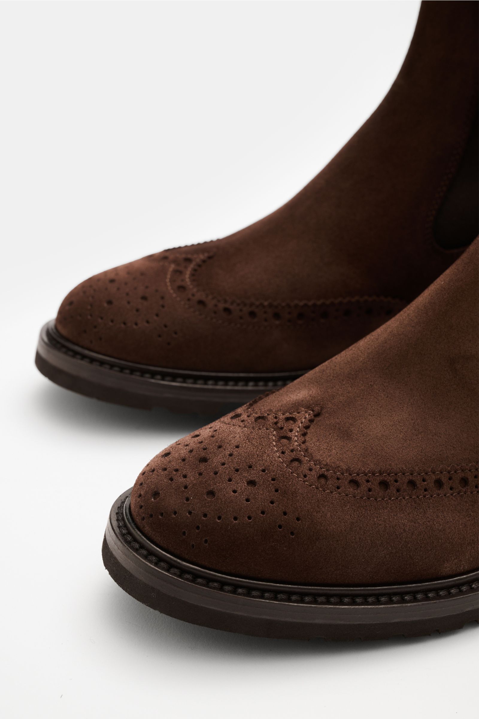 Close-up front-side view of the Henderson Chelsea Boot braun in rich brown suede with decorative perforations, sturdy black sole, and elegant tapered silhouette. Perfectly equipped for autumn: The Chelsea Boot by HENDERSON made of high-quality velour leat