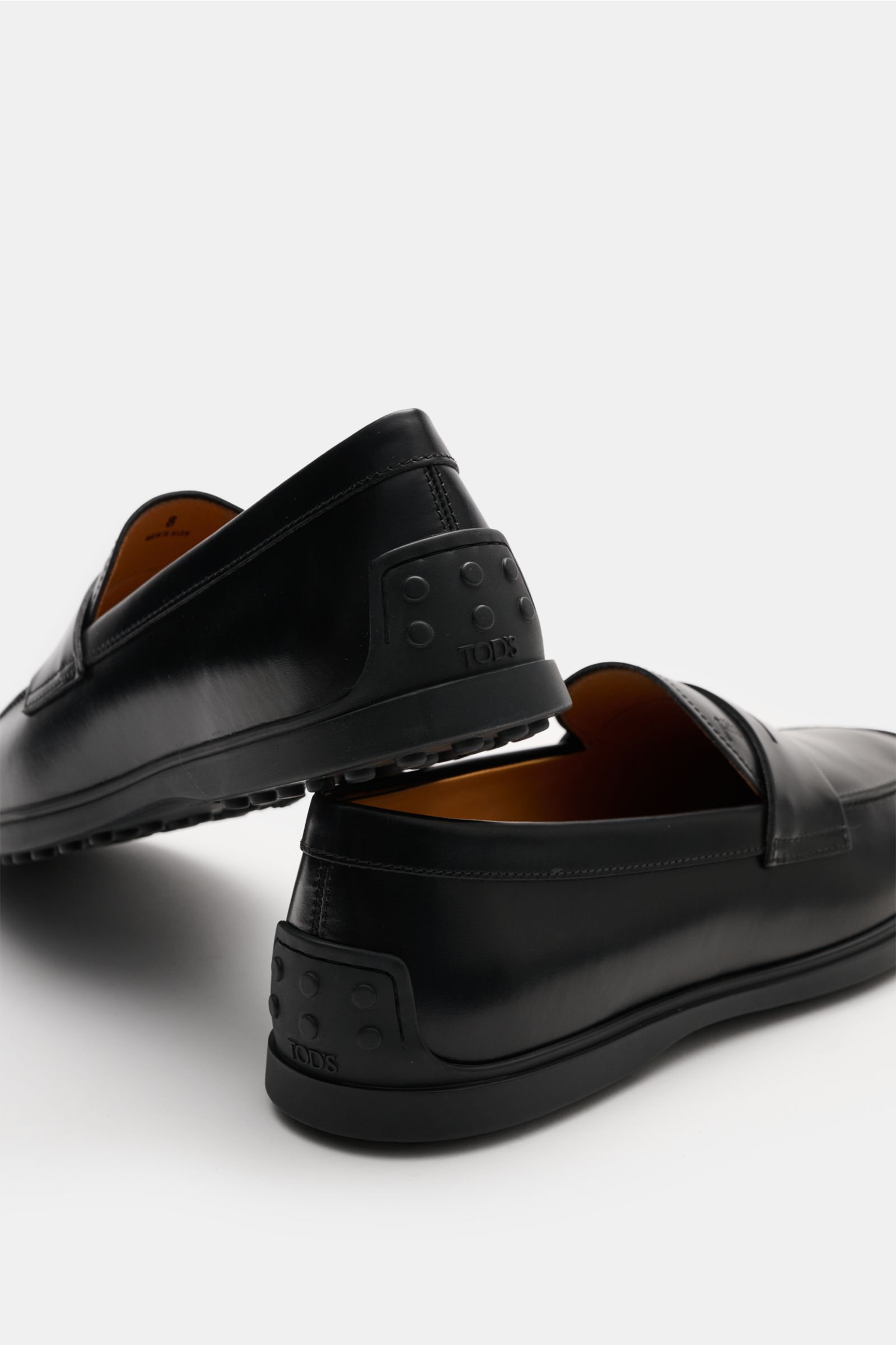 Tod's Penny Loafer schwarz, edles Glattleder, leicht schmal zulaufend, Penny Strap, Steppnaht vorne, Noppen an Ferse, Gummi-Laufsohle, seitliche Perspektive, made in Italy.