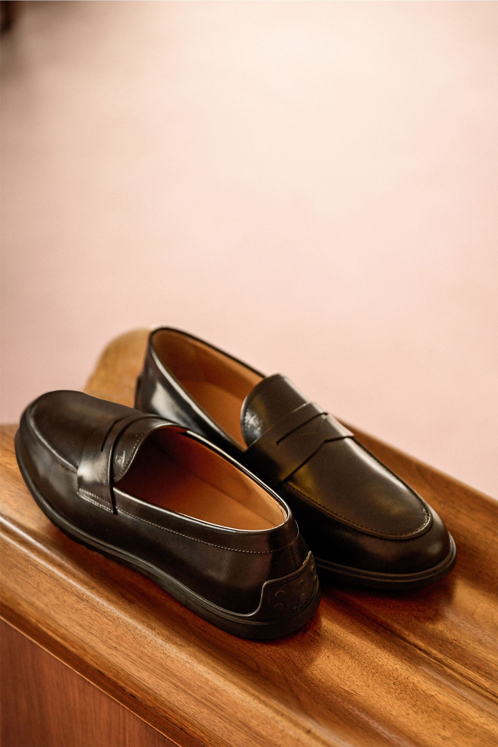 Tod's Penny Loafer schwarz aus edlem Glattleder, leicht schmal zulaufend mit typischem Penny Strap, Steppnaht, Noppendetail an Ferse, Gummisohle, made in Italy, seitliche Perspektive.