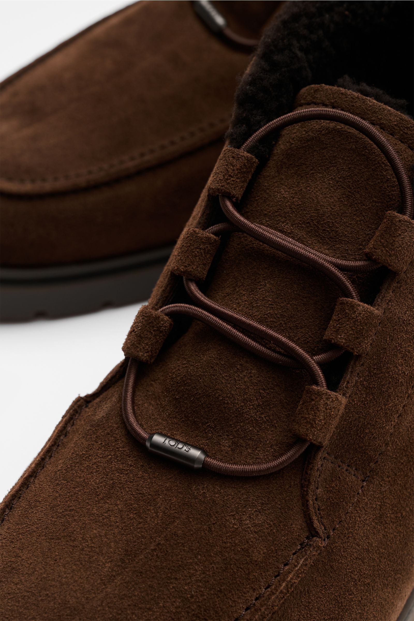 Tod's Boot dunkelbraun aus edlem Veloursleder mit elastischer Schnürung, Lammfell-Futter, Steppnaht und genoppter Gummisohle, Nahaufnahme von oben.