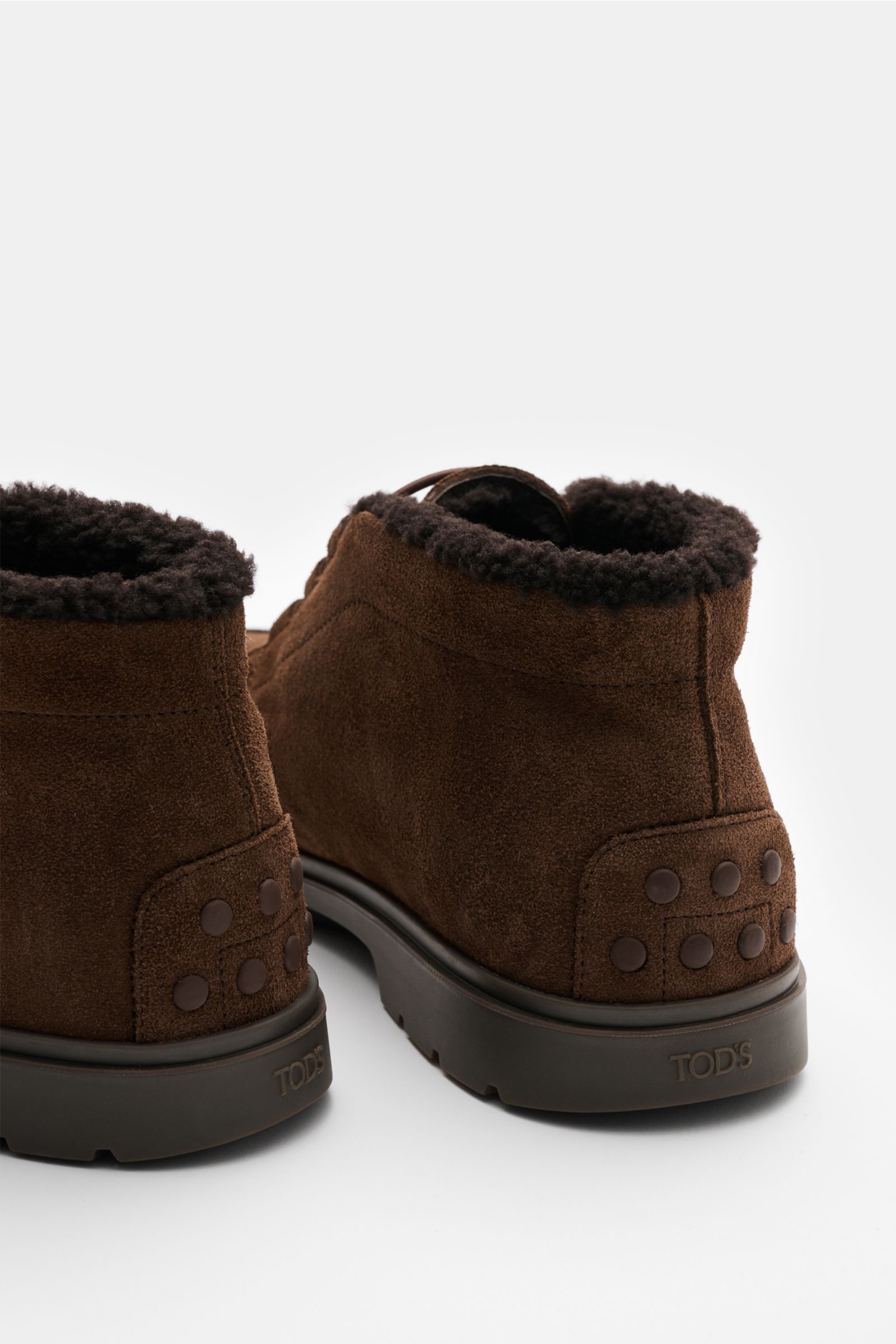 Tod's Boot dunkelbraun in Nahaufnahme von hinten, edles Veloursleder mit Lammfell-Futter, genoppte Gummisohle, elastische Schnürung.
