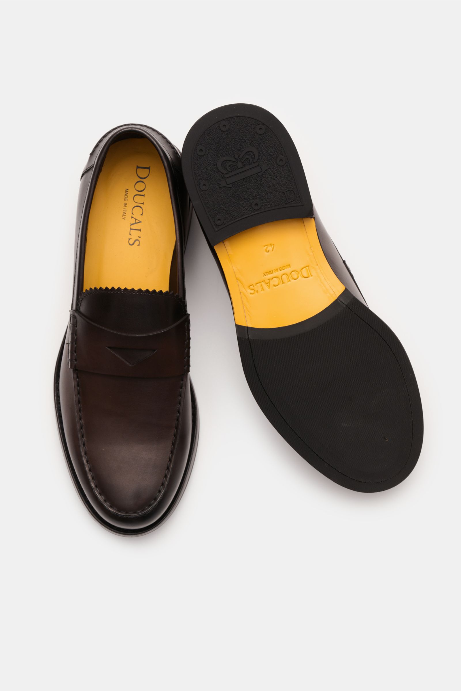 Doucal's Penny Loafer 'Deco' dunkelbraun shown from above, left shoe top view and right shoe sole view, featuring feines Glattleder, leicht schmal zulaufend, typischer Penny Strap, Vorderkappe mit Steppnaht, ledernes Innenfutter, and robuste Sohle aus Kau