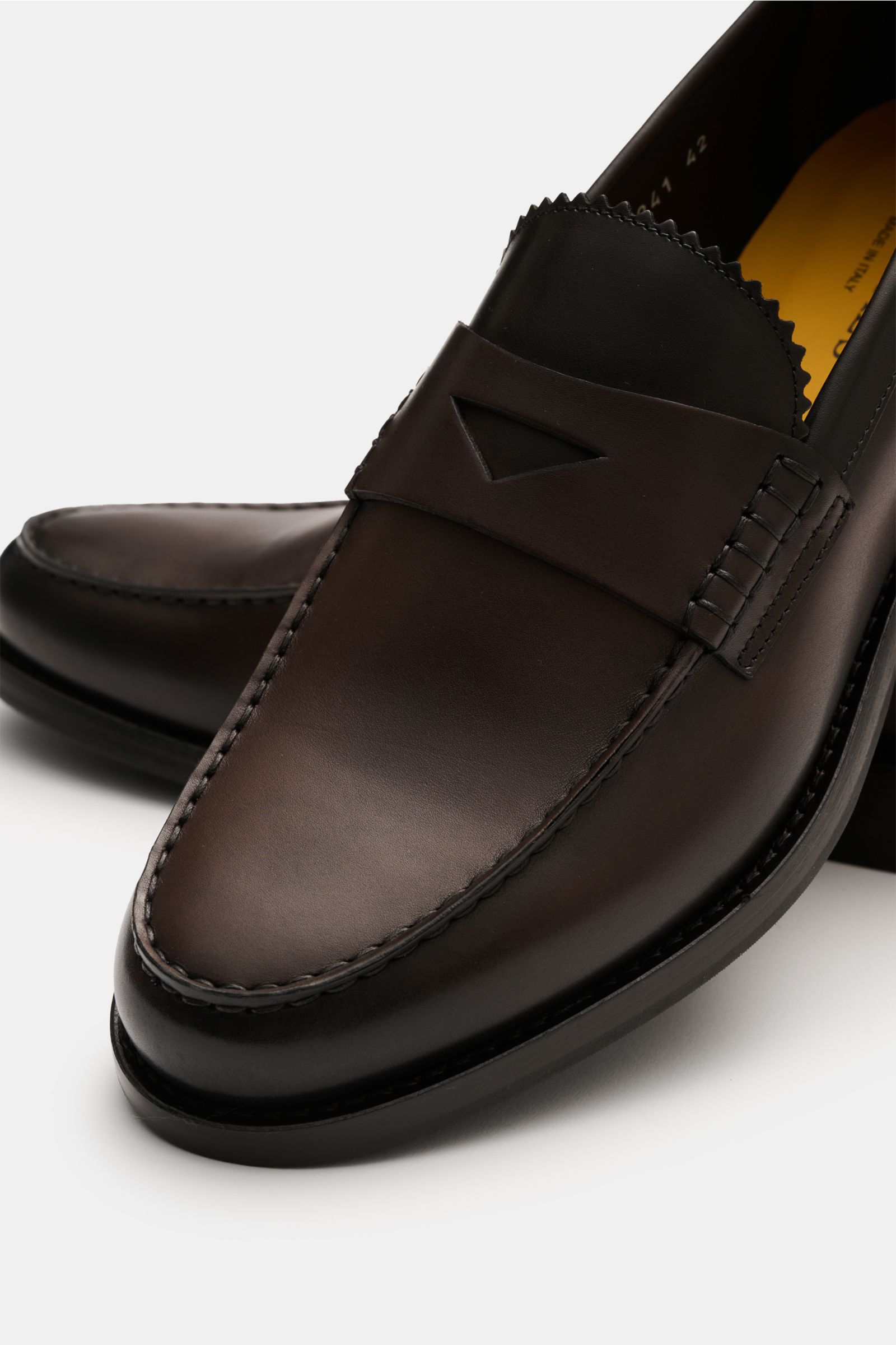 Close-up front-side view of Doucal's Penny Loafer 'Deco' dunkelbraun in fine smooth leather, slightly tapered, with typical penny strap, stitched toe cap, leather lining, and sturdy rubber sole.