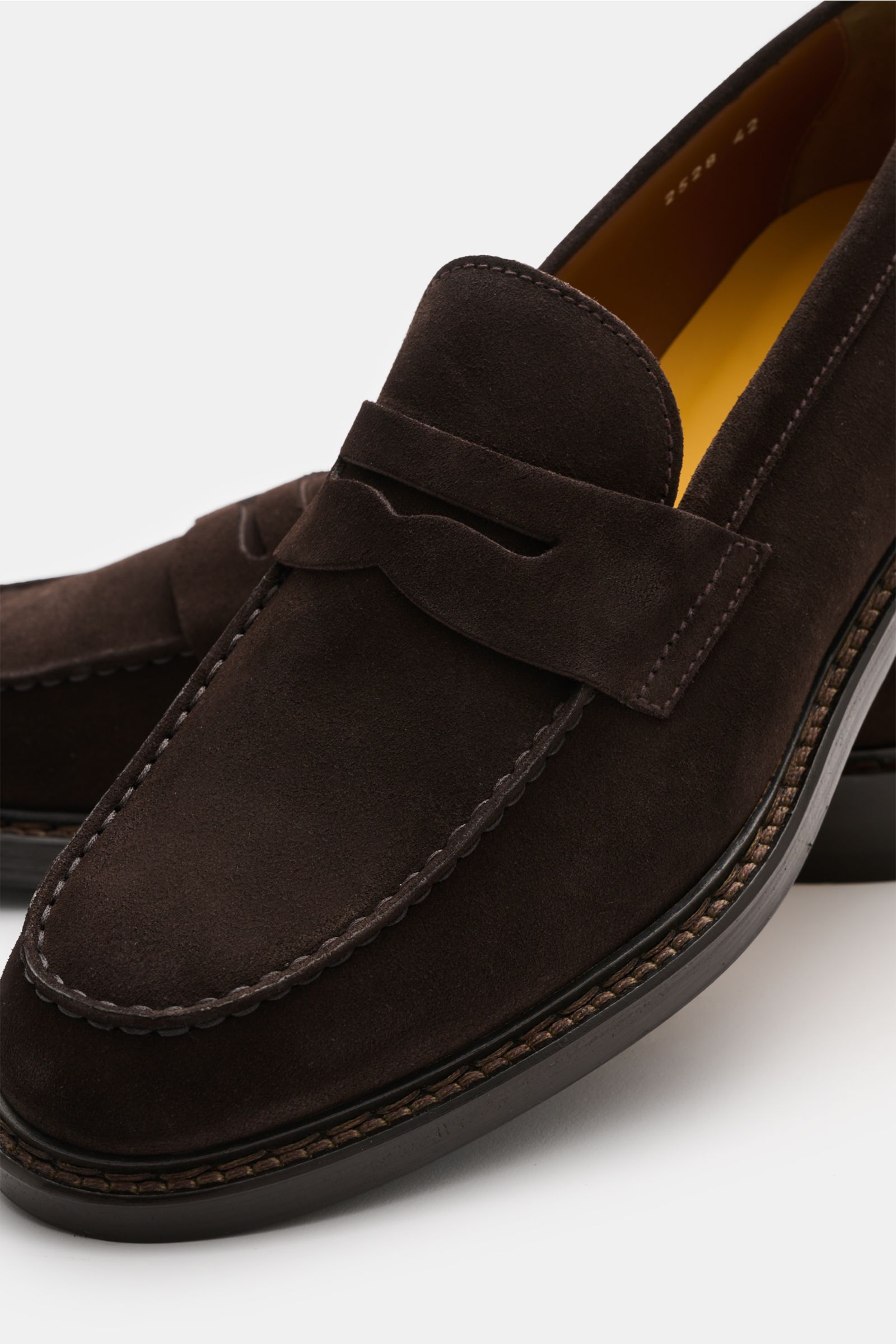 Close-up front-side view of Doucal's Penny Loafer 'Visone' dunkelbraun in feines Veloursleder, leicht schmal zulaufend, typischer Penny Strap, Vorderkappe mit Steppnaht, ledernes Innenfutter, robuste Sohle aus Kautschuk.