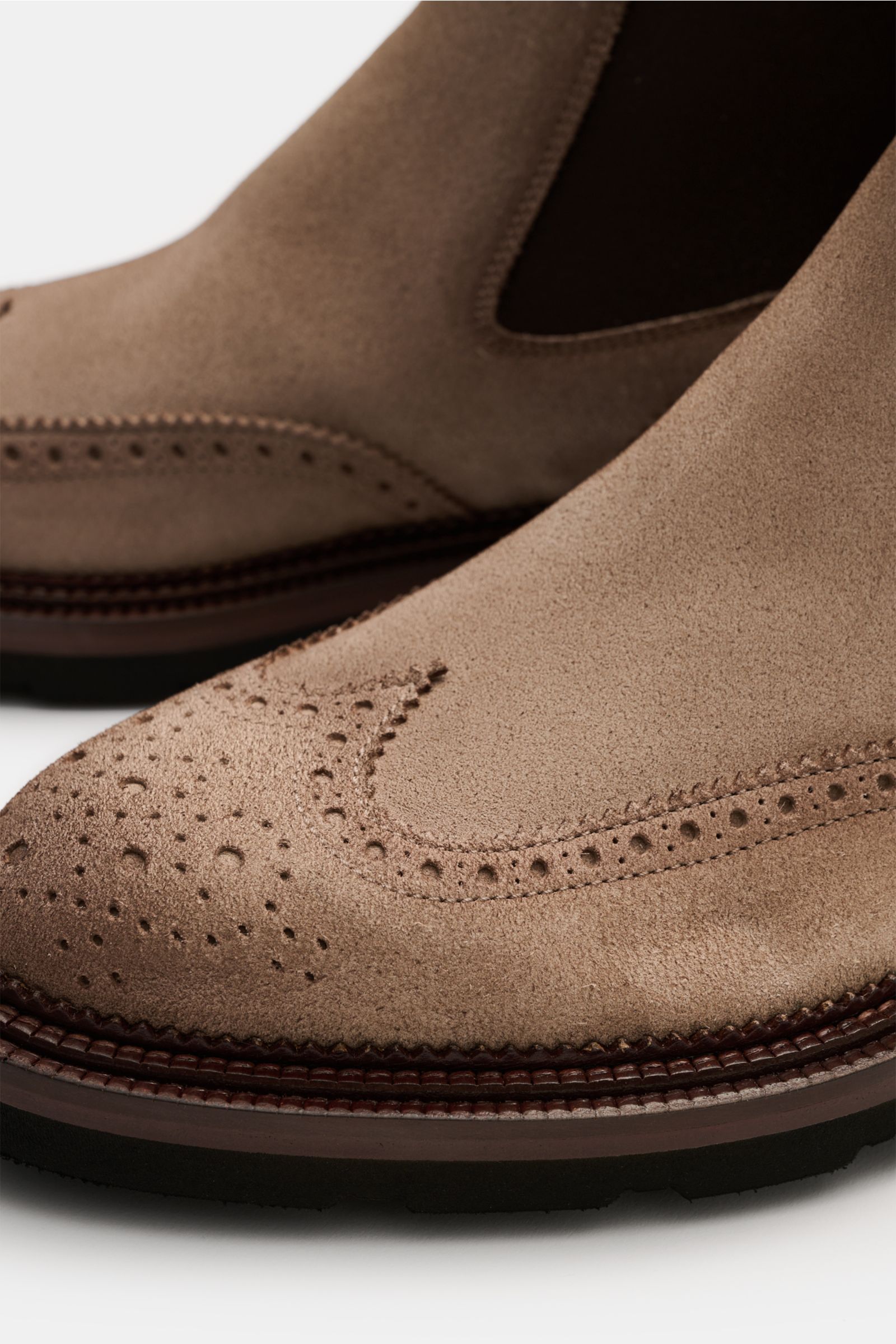 Santoni Chelsea Boot 'Colin' beige aus Veloursleder, schmal zulaufend, mit Wingtip und Broguings, Gummi-Laufsohle, seitlich elastisch, Nahaufnahme frontal.