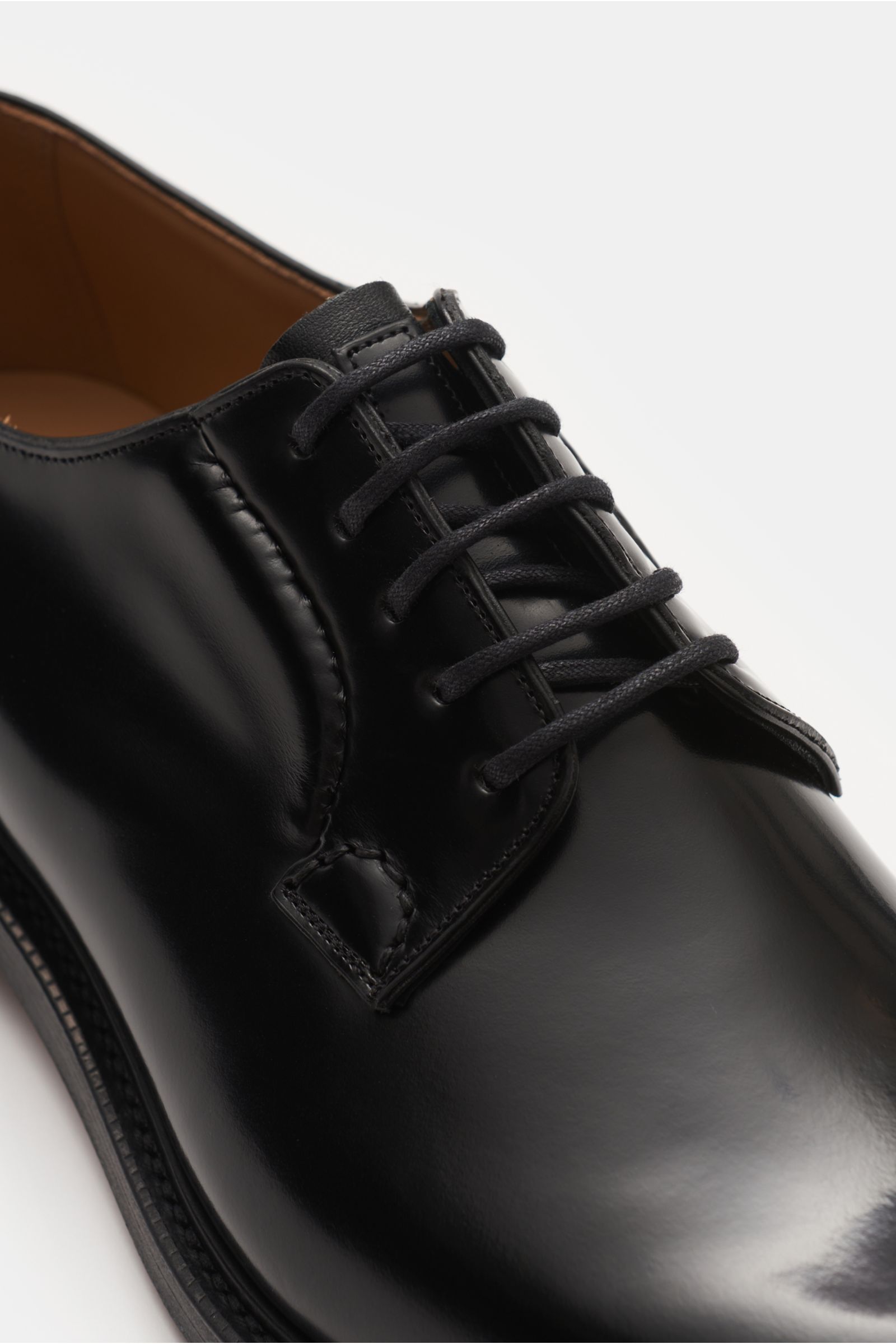 Close-up front-side view of Church's Derby 'Shannon' schwarz shoe in polished calf leather, Goodyear-welted, slightly tapered toe cap, open five-eyelet lacing, leather lining, leather sole, and rubber-reinforced heel.