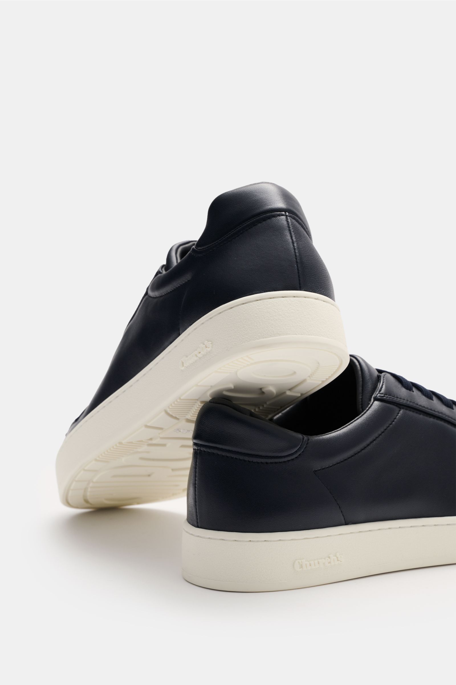 Church's Sneaker 'Ludlow' navy aus geschmeidigem Nappaleder, schmal zulaufend, elastische Schnürung, gepolsterter Schaftrand, Logo auf Lasche, ledernes Innenfutter, Kautschuksohle, fotografiert von hinten seitlich.