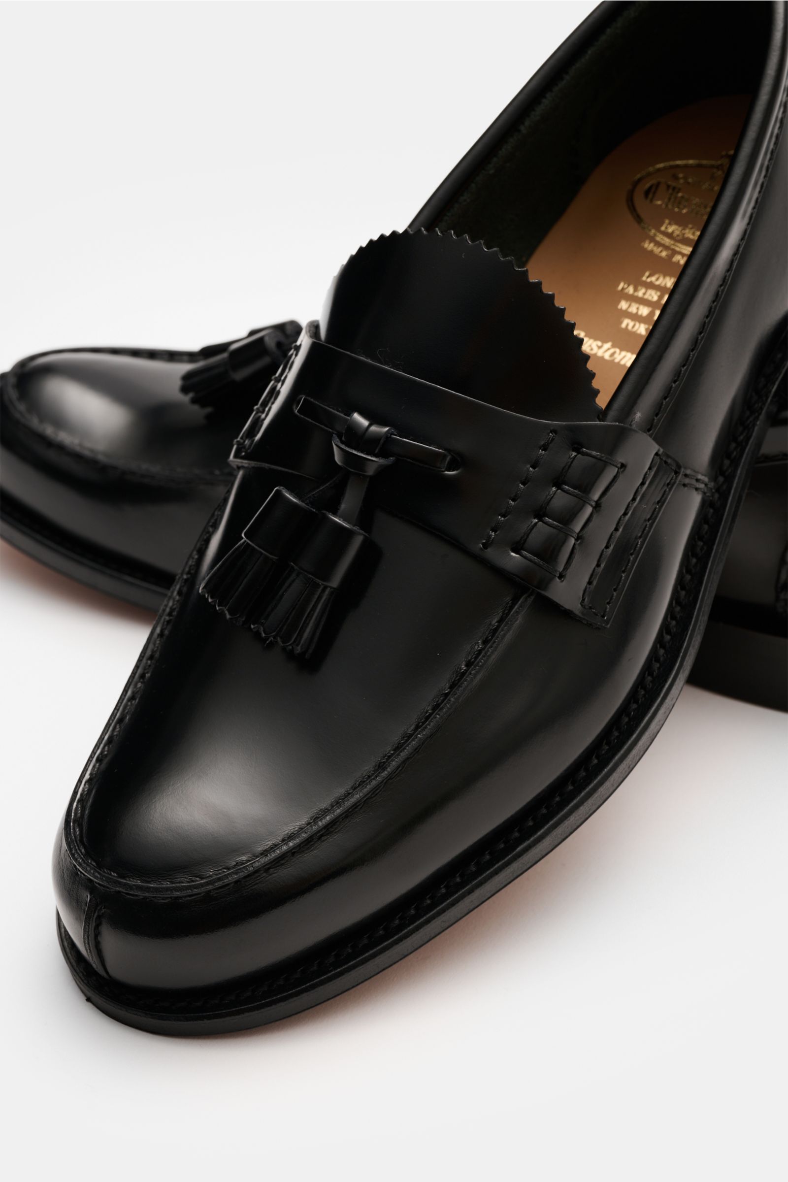 Church's Tassel Loafer 'Tiverton' schwarz, poliertes Glattleder, Ziernähte, typische Tassels, ledernes Innenfutter, seitliche Nahaufnahme.
